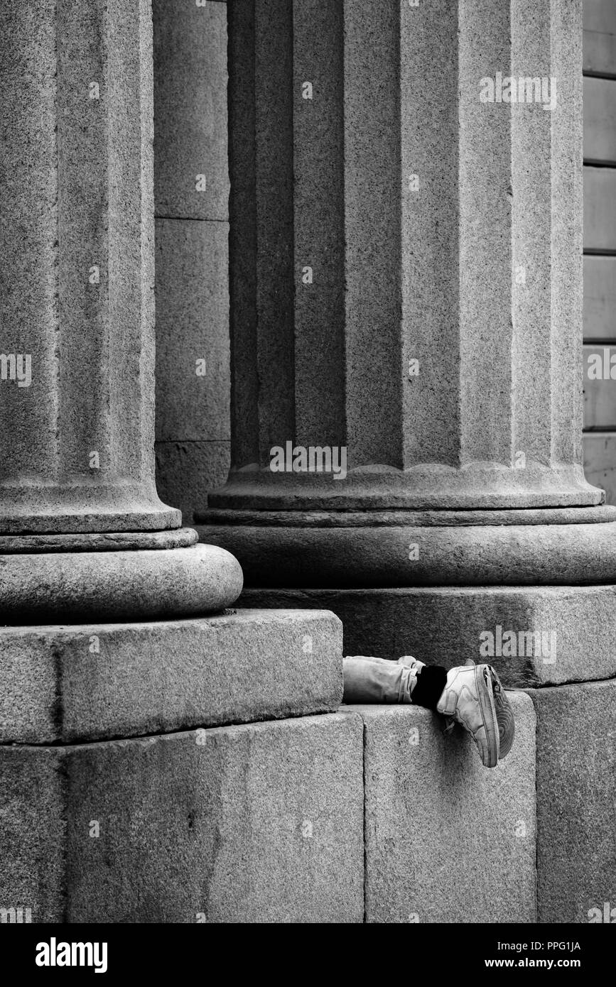 Beine einer Person liegen zwischen antiken Säulen Stockfoto