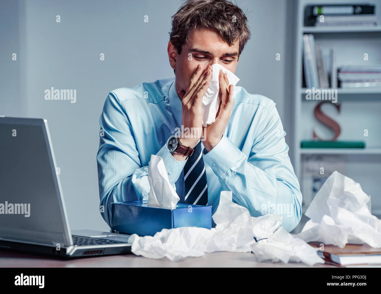 Kranke Arbeitnehmer seine Nase in Papiertaschentücher blasen. Foto junger Mann bei der Arbeit im Büro. Geschäftskonzept. Stockfoto