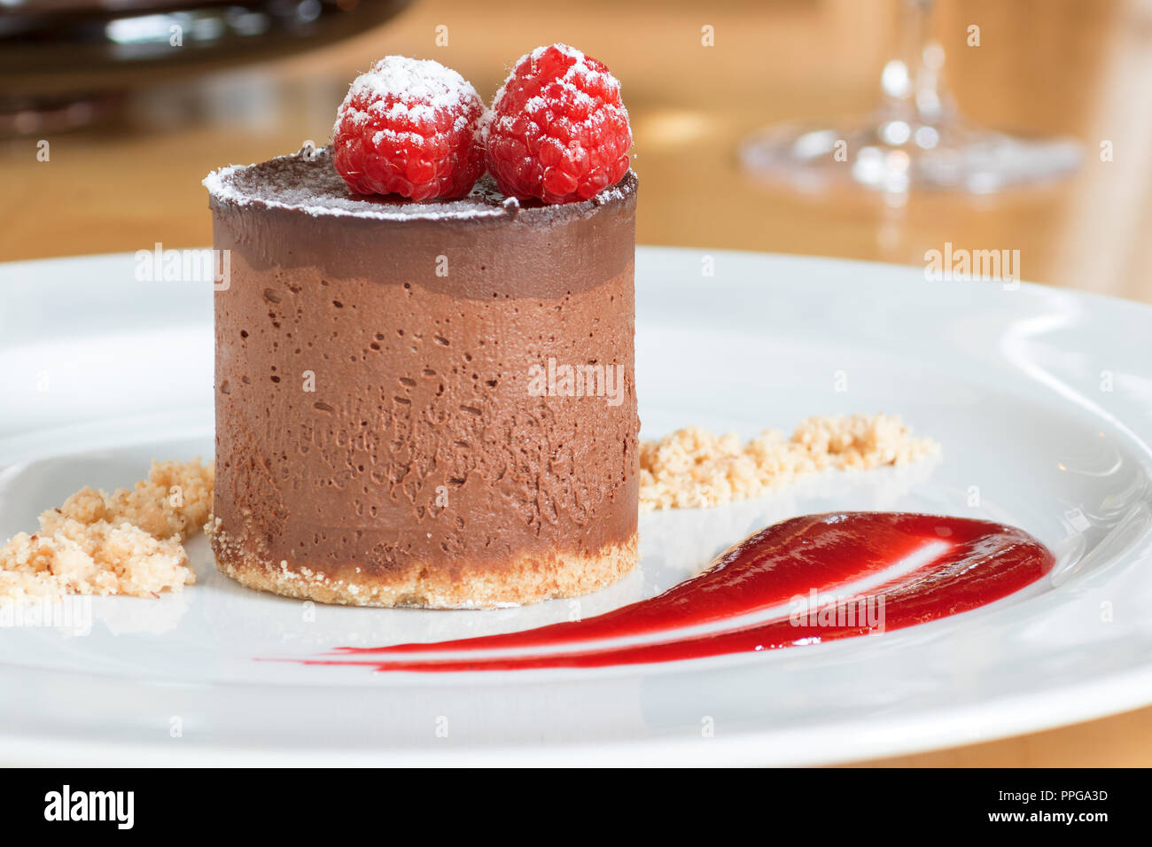Mousse au Chocolat auf weiße Platte mit 2 Himbeeren auf der Oberseite dekoriert und mit Puderzucker bedeckt. Die Platte dekoriert von Keks und Krümel raspber Stockfoto