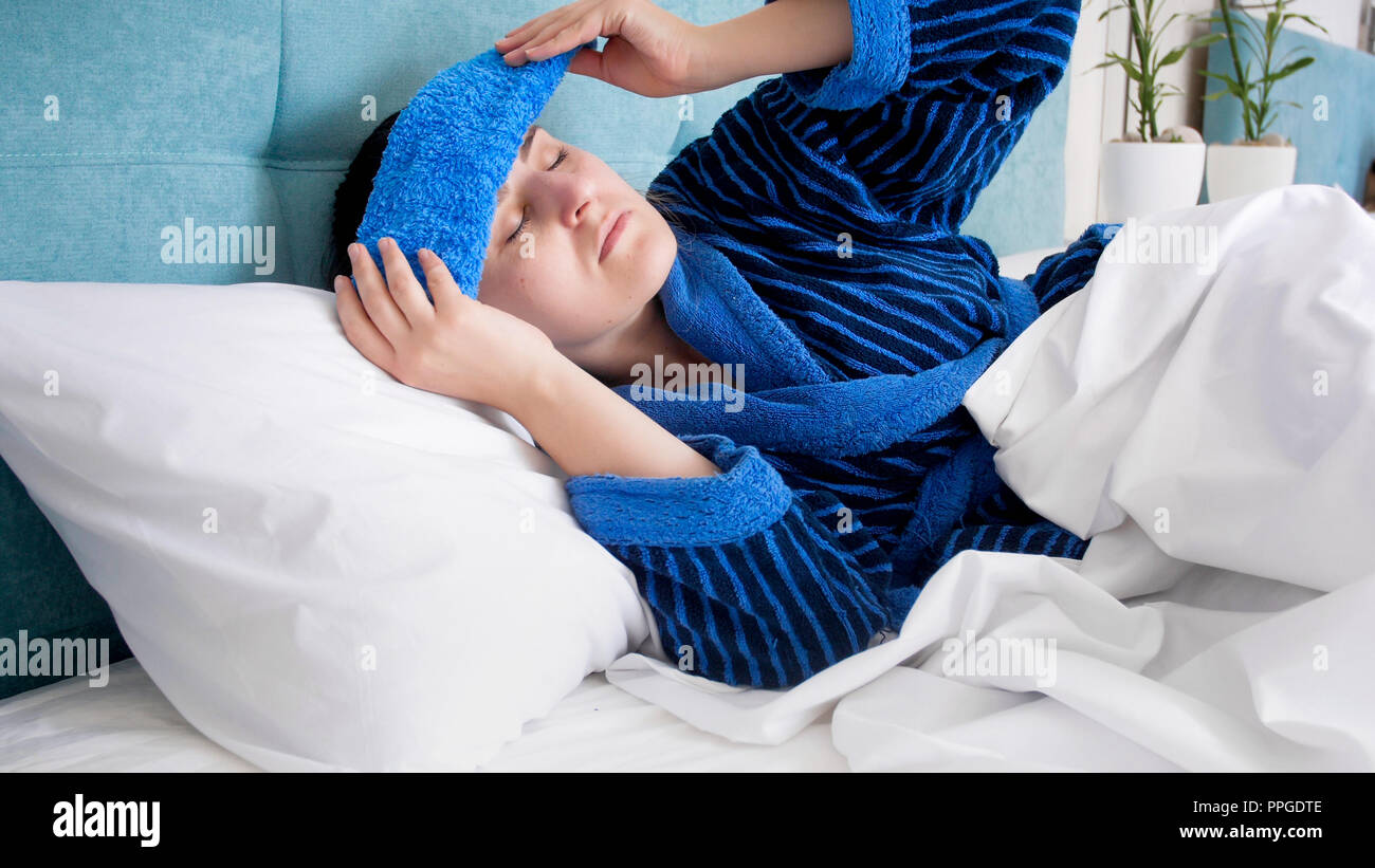 Portrait von kranken Frau nach Kneipe leiden unter Kopfschmerzen, kalten  nassen Handtuch auf der Stirn Stockfotografie - Alamy