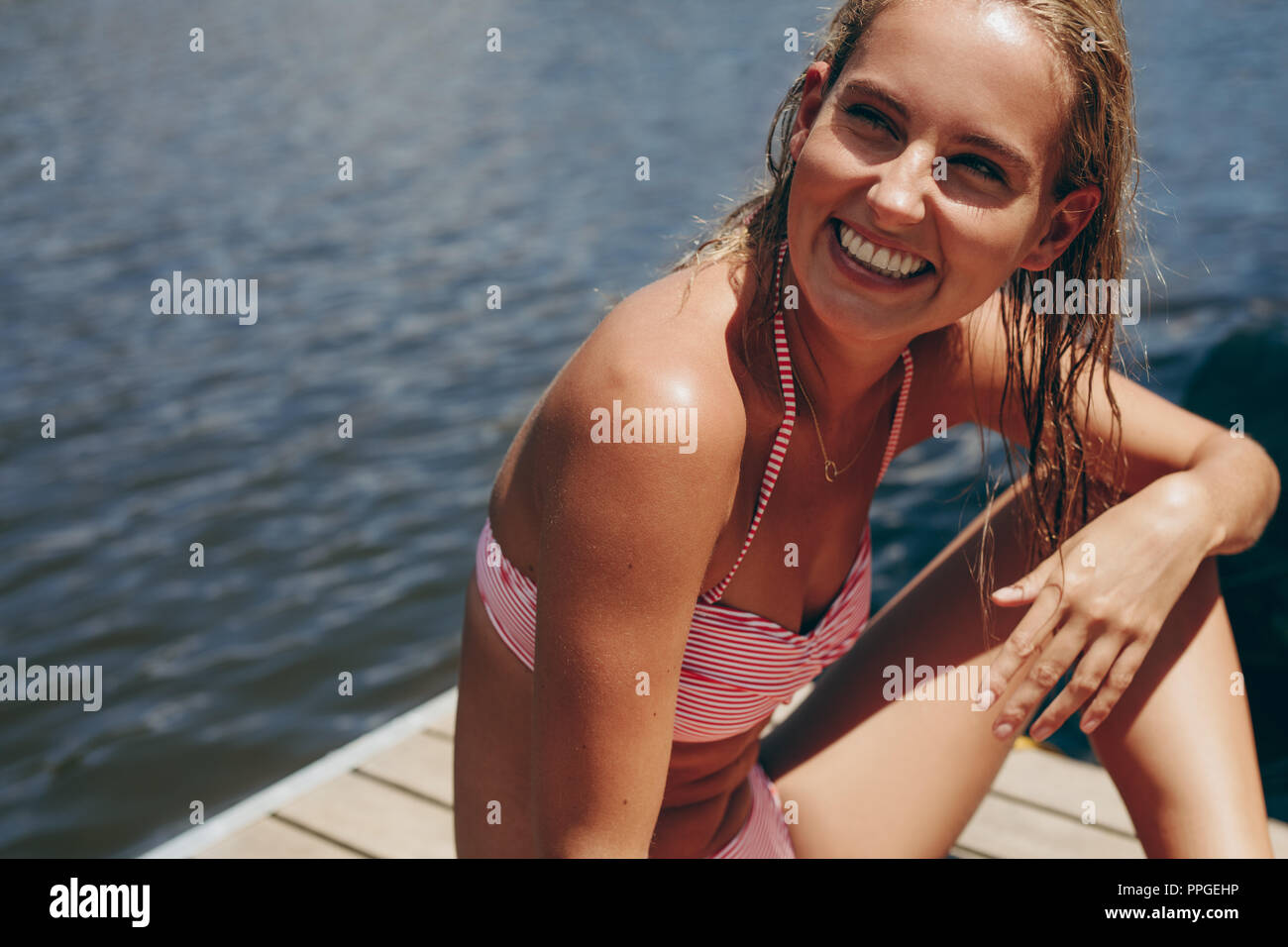 Frau im Bikini geniessen Sie Ihre Ferien an einem See. Frau im Badeanzug auf einem schwimmdock an einem See. Stockfoto