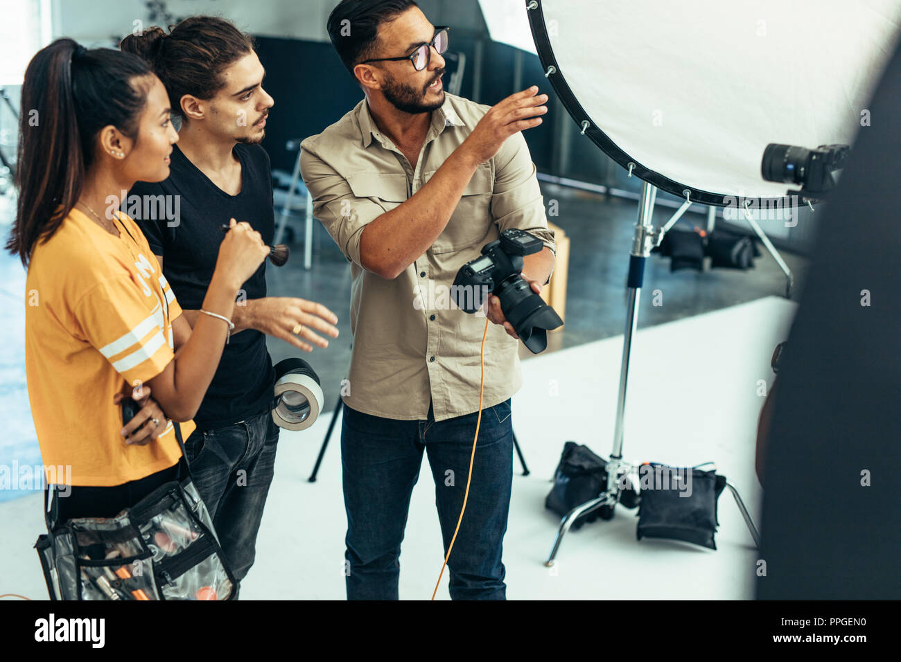 Fotograf erklären, über den Schuß zu sein Team im Studio. Fotograf mit seinem Assistenten, die eine Kamera während ein Foto schießen. Stockfoto