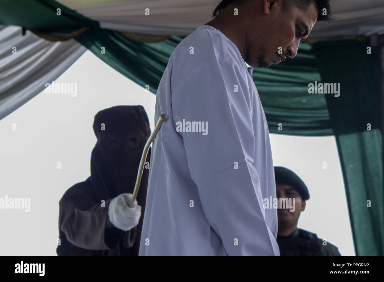 Lhokseumawe, Aceh, Indonesien. 25 Sep, 2018. Ein Mann gesehen in öffentlichen gepeitscht wird für das Spielen der betrachtet wird, die islamische Scharia zu verletzen. Obgleich betrachtet die Internationale Konvention gegen die grausame, unmenschliche oder Folter und Grausamkeit zu verletzen. Aceh, einer der Provinzen in Indonesien, die darauf besteht, die Durchführung von Schlagsahne als eine Provinz der islamischen Scharia. Credit: Maskur hat/SOPA Images/ZUMA Draht/Alamy leben Nachrichten Stockfoto