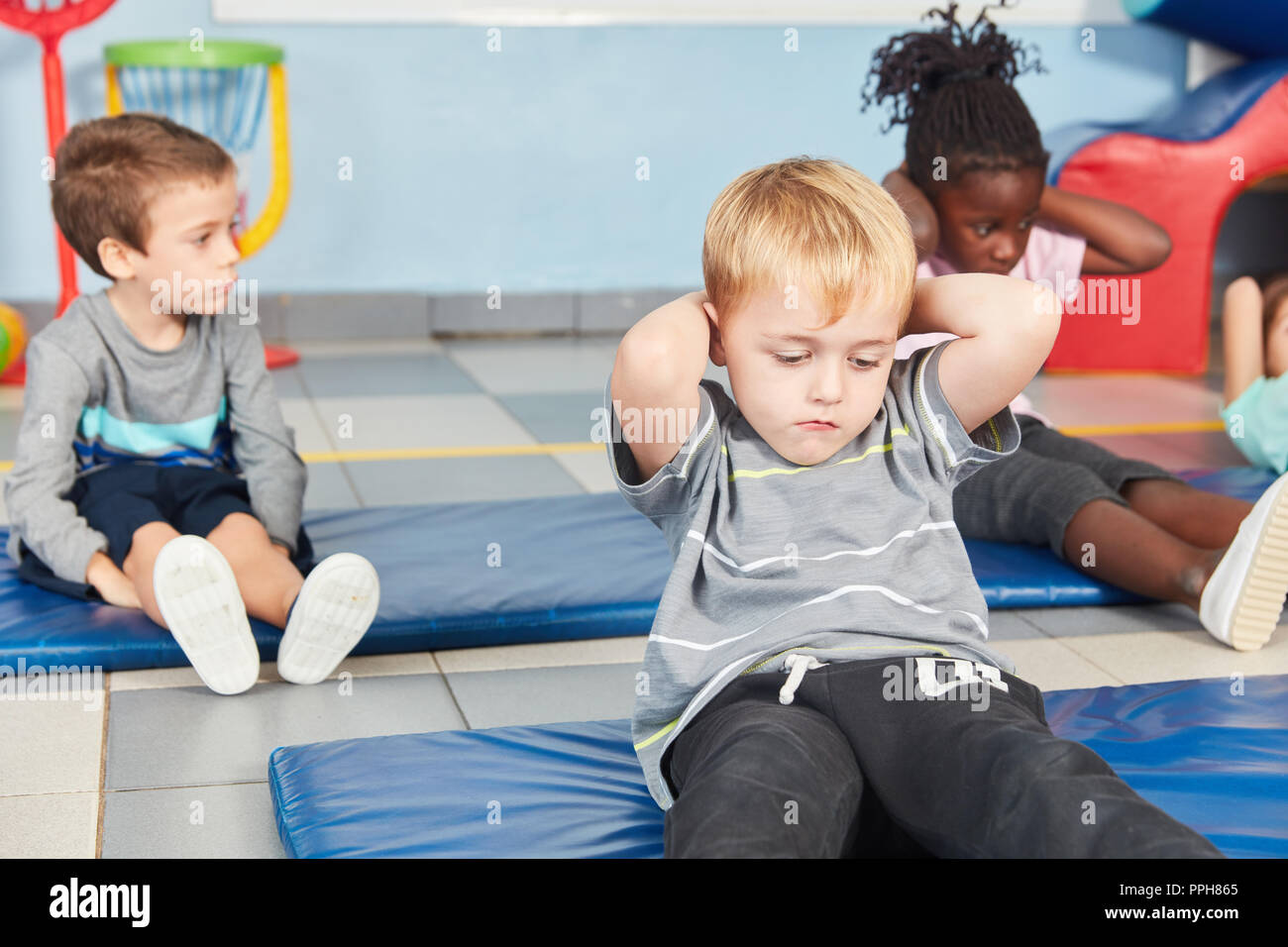 Kinder Sit-up Übung im Sportunterricht an der Turnhalle in der Grundschule Stockfoto