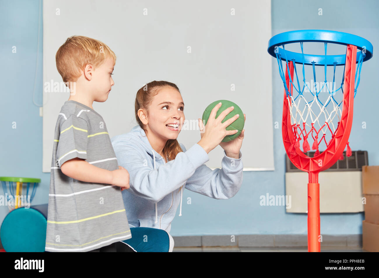 Frau als Sportlehrer und Jungen in der Turnhalle an der Grundschule Basketball Training Stockfoto