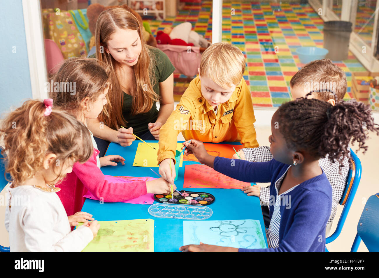 Kinder Gruppe Farben mit Wasser Farbe in der Malerei Klasse im Kindergarten zusammen mit Erzieherin Stockfoto