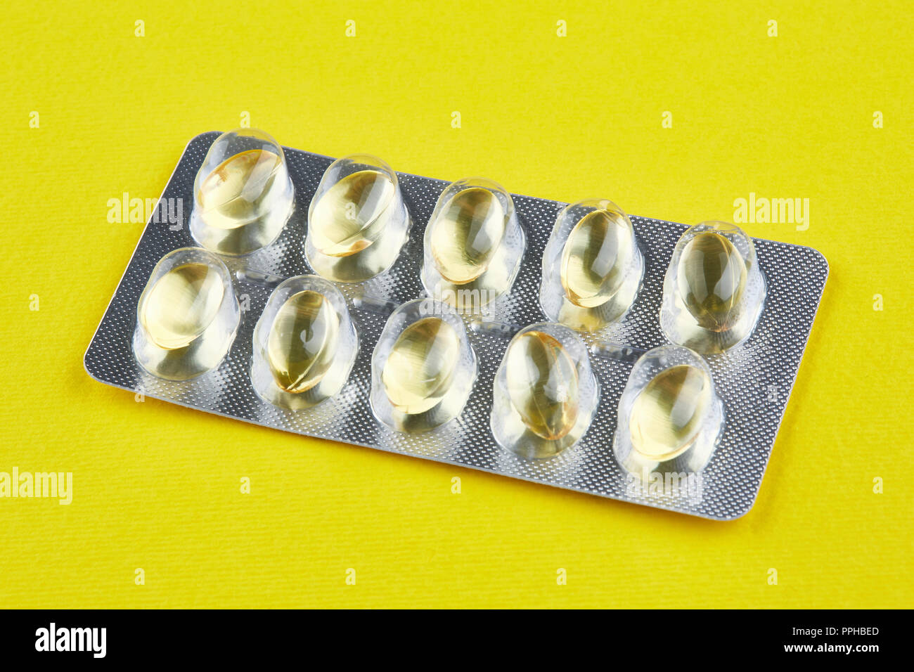 Versiegelte Packung mit transparenter Kapseln auf gelben Hintergrund. Vitamine. Stockfoto