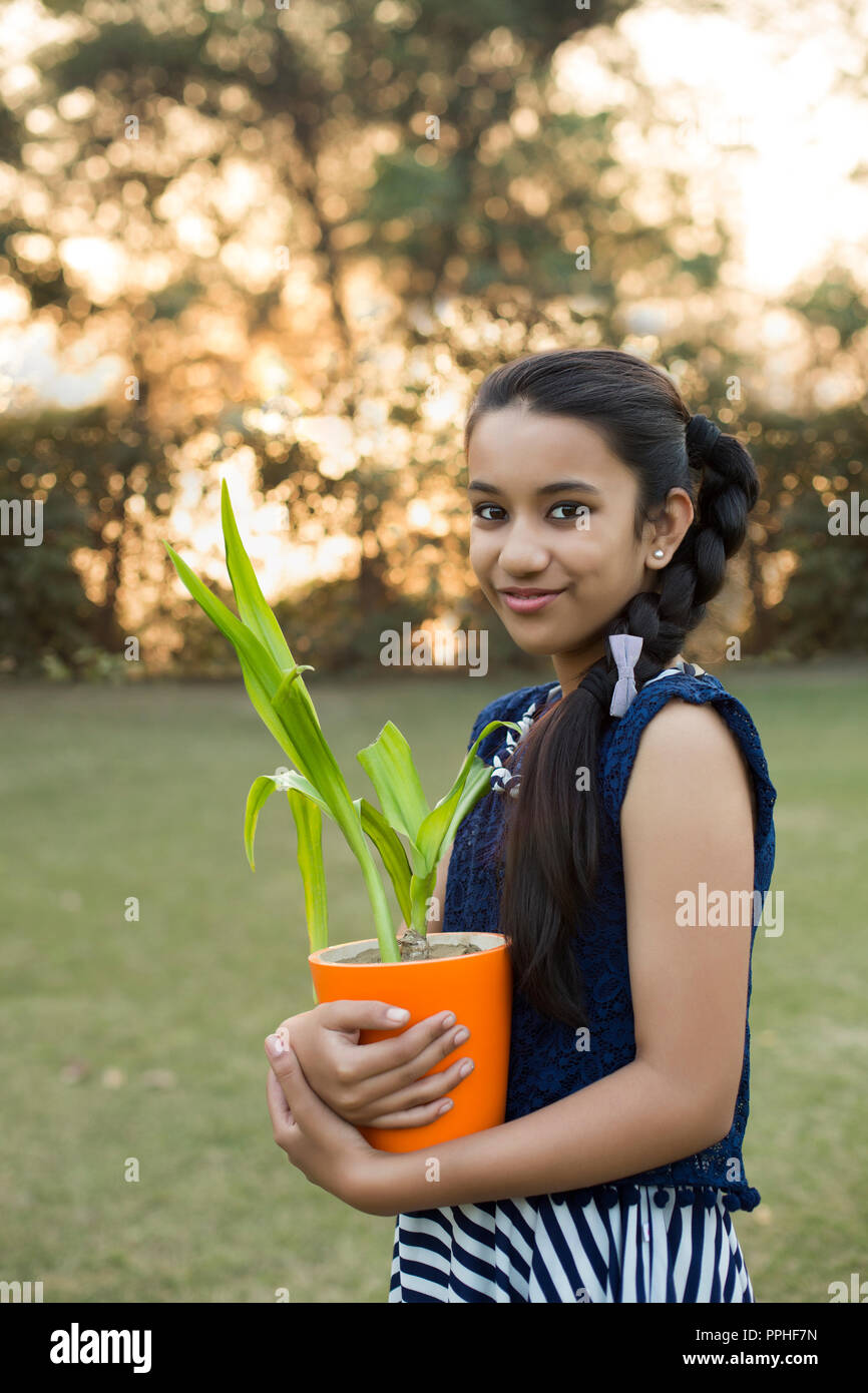 Lächelnden jungen Mädchen einen kleinen Blumentopf in der Hand im Park. Stockfoto