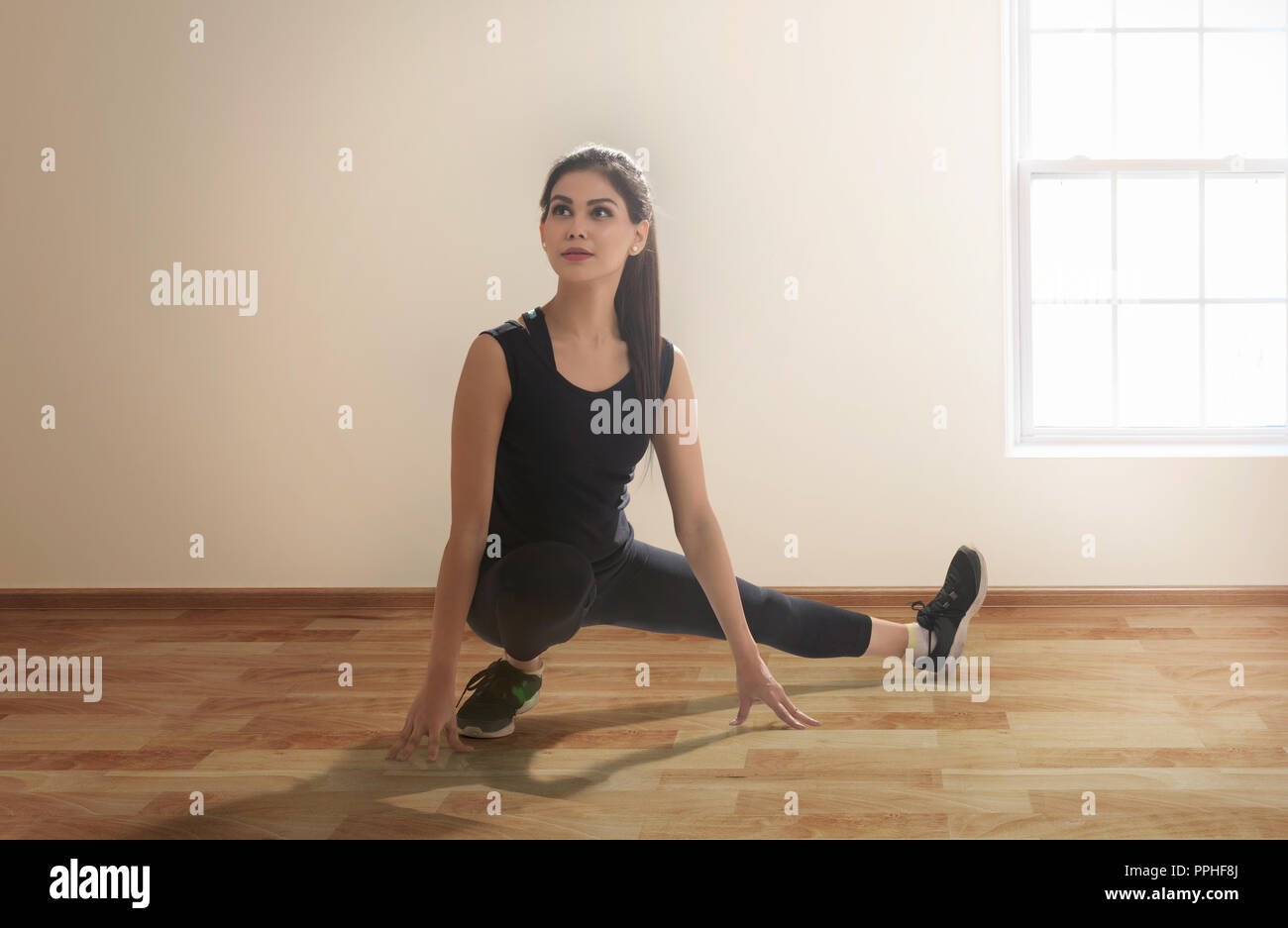 Junge Frau in Sportklamotten tun leg stretching Übungen auf dem Boden. Stockfoto