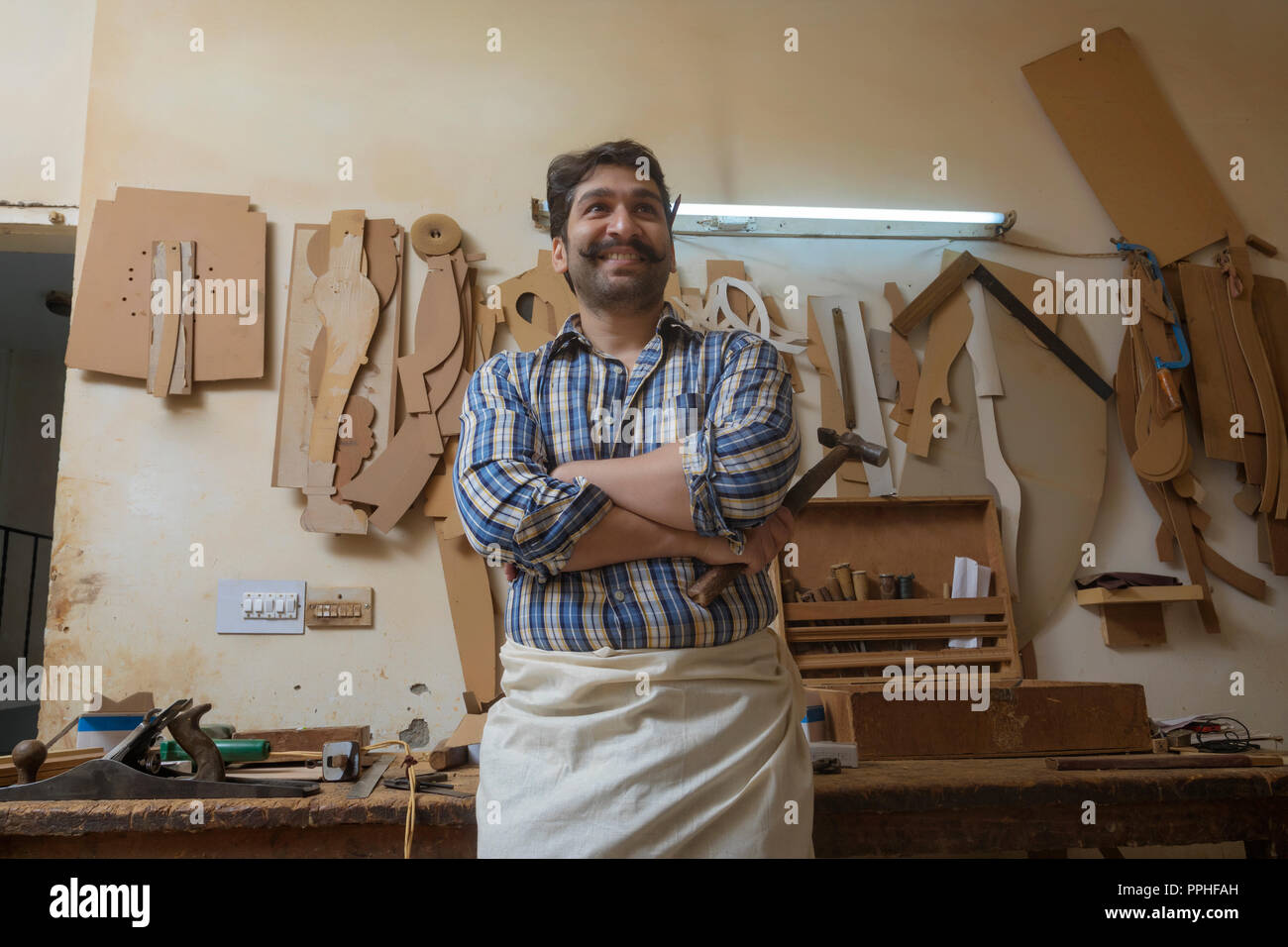 Zimmermann in seiner Werkstatt mit einem Hammer mit gekreuzten Armen weg schauen. Stockfoto