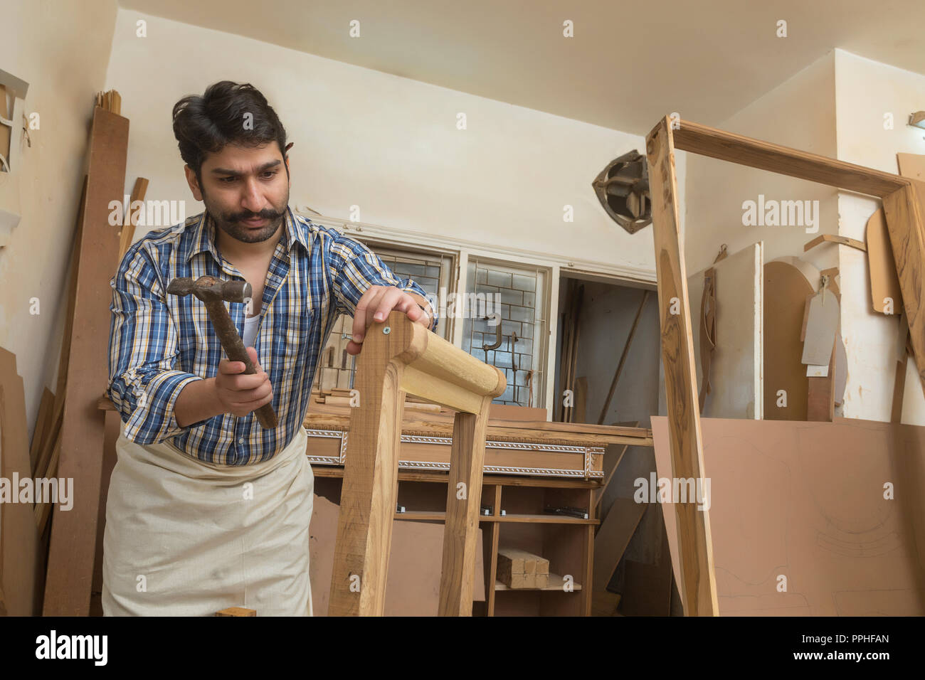 Tischler schlagen einen Nagel auf Holz mit Hammer in seiner Werkstatt. Stockfoto