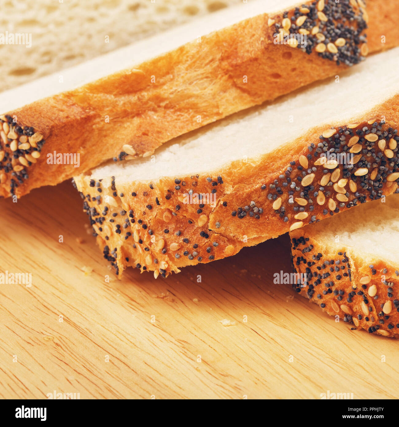 in Scheiben Weißbrot mit Mohn auf Schneidebrett Stockfoto