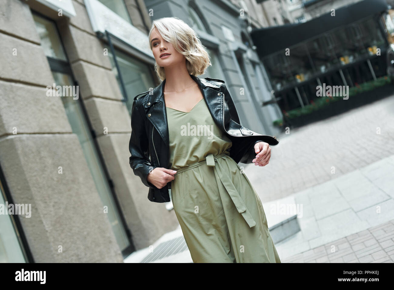 Mode. Junge stilvolle Frau, die zu Fuß auf der Straße zur Seite schauen, lächeln, neugierig Stockfoto