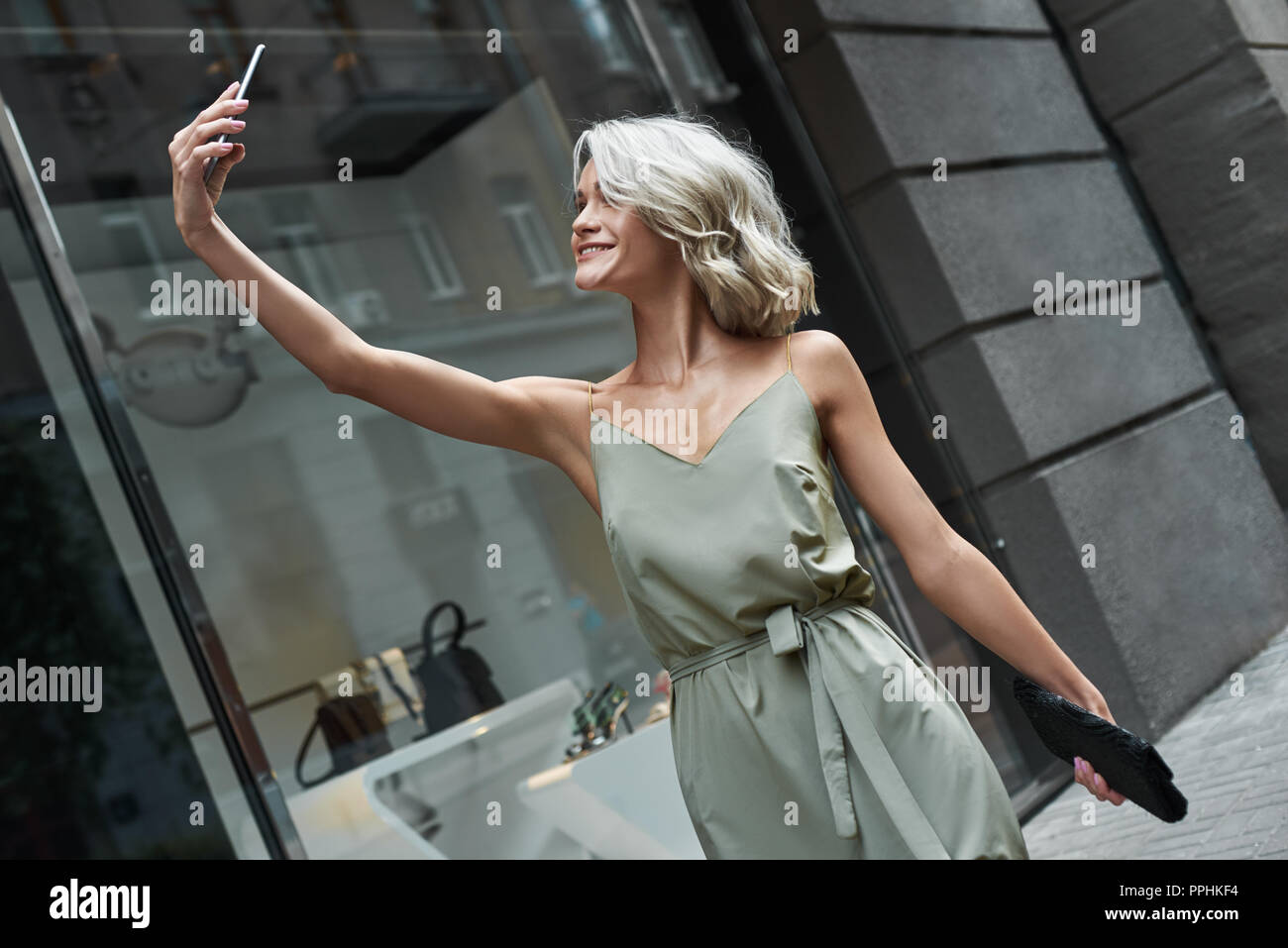 Mode. Junge stilvolle Frau gehen auf die Straße der Stadt, die auf dem Smartphone selfie Foto lächelt Fröhlich Stockfoto