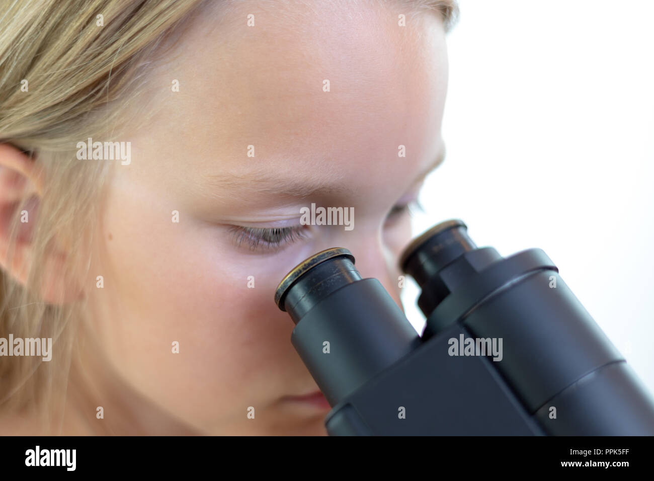 Eine Blondine 9 Jahre alten Schulkind schaut in das Okular eines Mikroskops. Isoliert Stockfoto