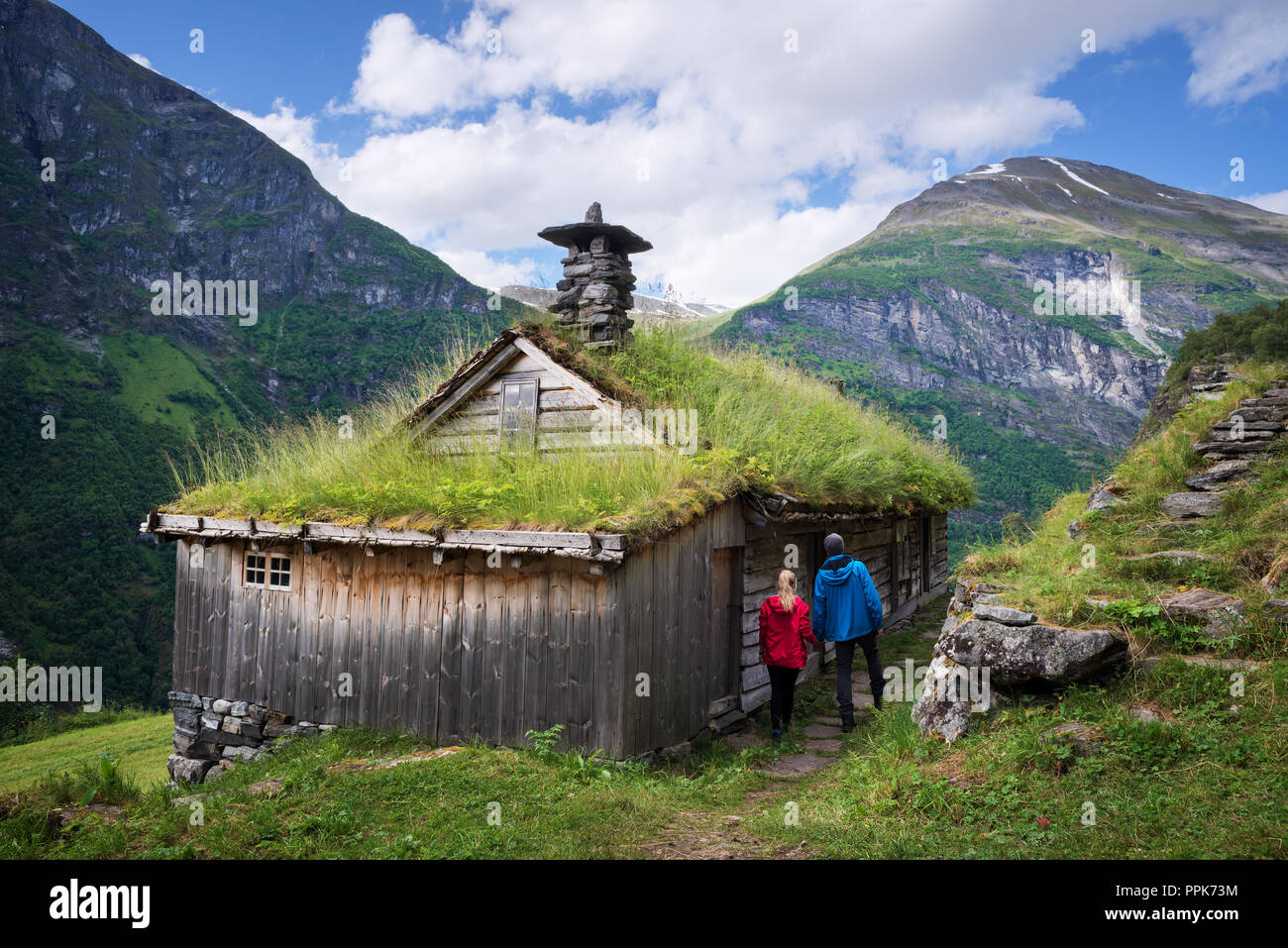 Kagefla - Berg Bauernhöfe mit Rasen Häuser entlang der Geiranger Fjord. Touristische Attraktion von Norwegen. Ein paar Reisende, traditionelle Sca Stockfoto