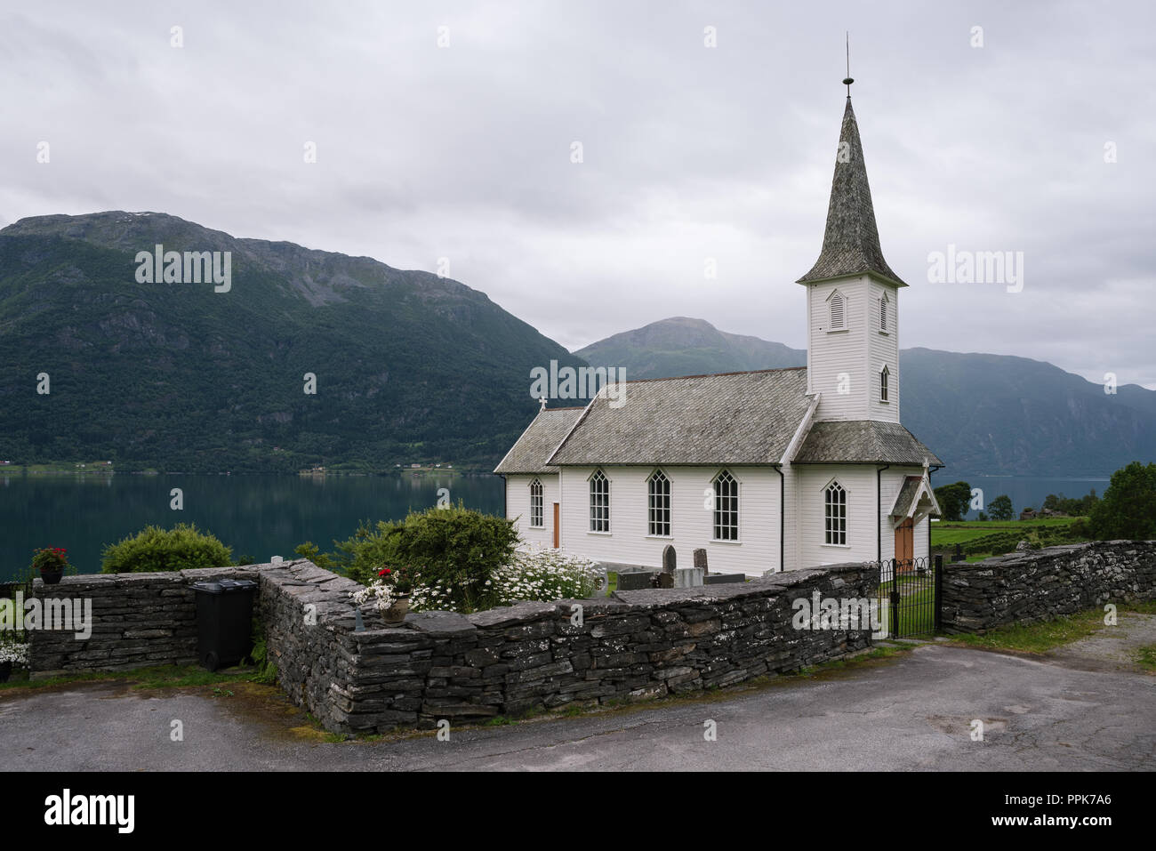 Norwegische Kirche - Nes kyrkje, Gemeinde Glanz, Norwegen. In der Nähe von Fjord Lusterfjord. Old Stone Zaun. Bedeckt nördlichen Wetter Stockfoto