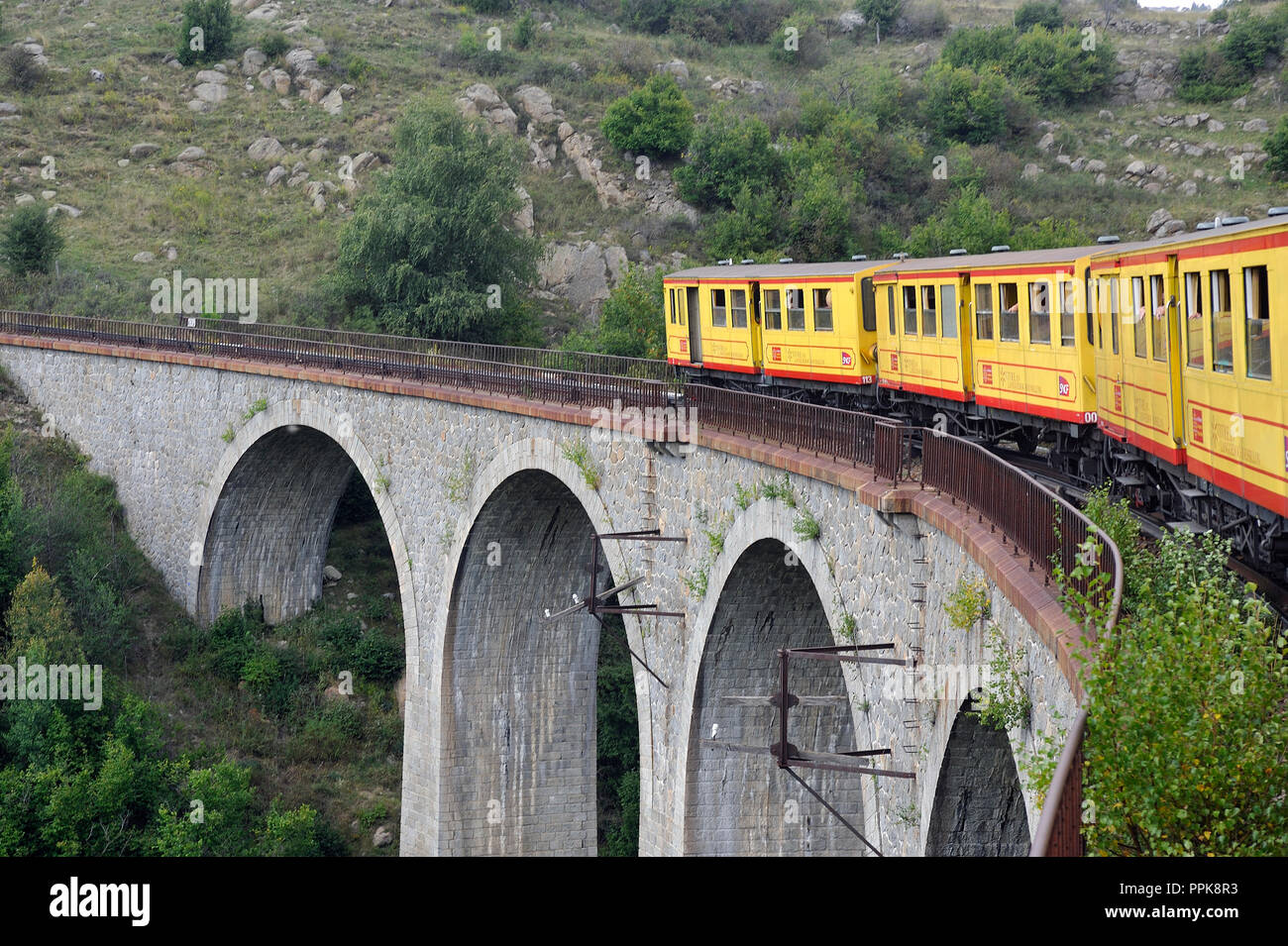 Der kleine gelbe Zug der Pyrenäen Überquerung einer wunderschönen Berglandschaft Stockfoto