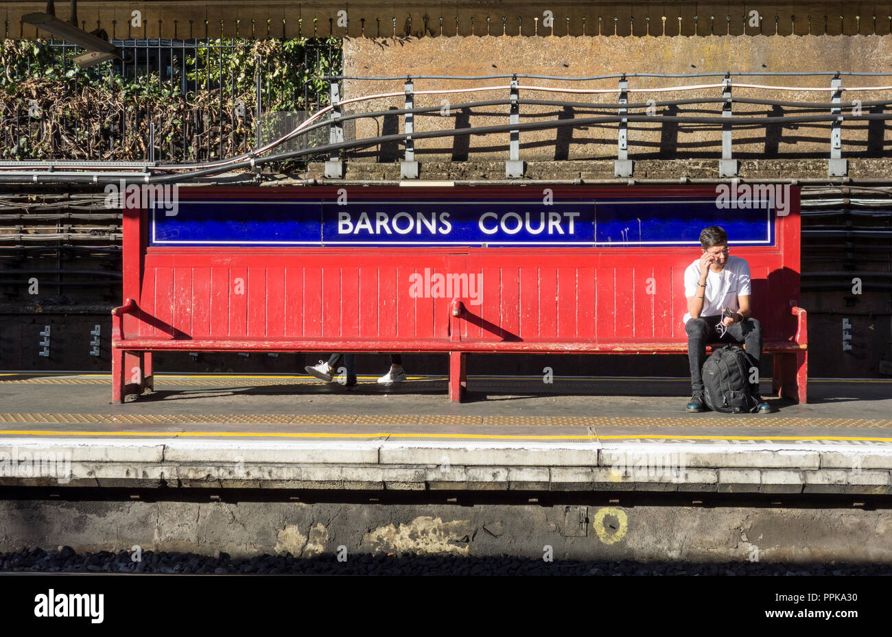 Eine alte hölzerne Plattform Bank auf Barons Court U-Bahnstation, Barons Court, London, UK Stockfoto