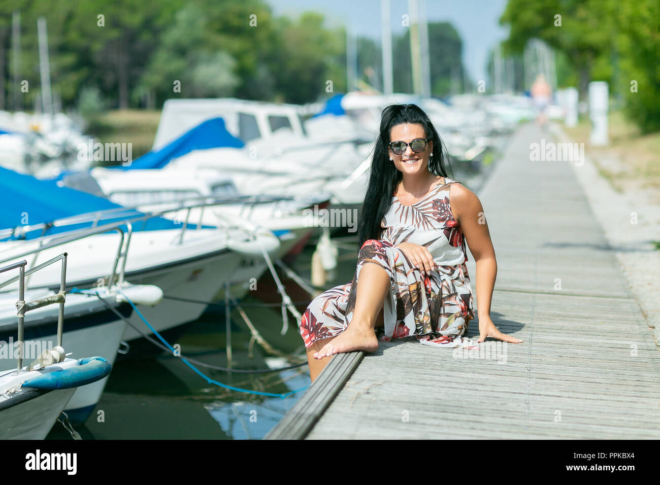 Stilvolle Junge Frau sitzt auf den Wald Pier. Konzept Sommerferien Stockfoto