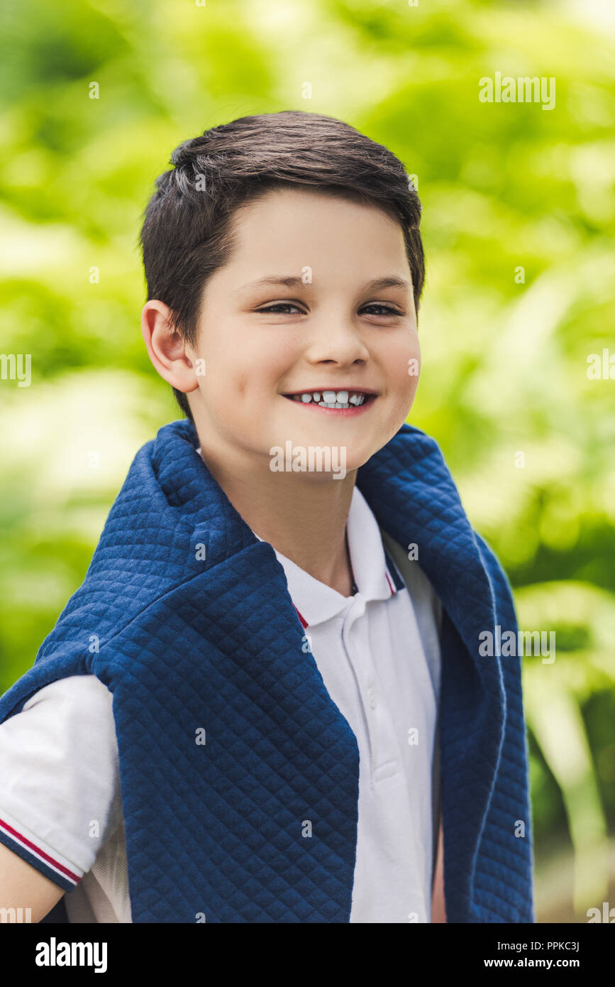 Lächelnd Kind mit Überbrückungskabel von der Kamera über die Schulter schauen Stockfoto