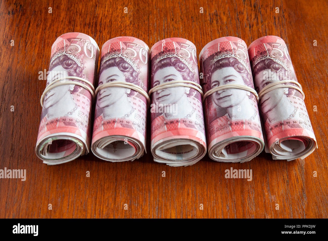 Aus Geld auf den Tisch. 5.000 £ Sterling in fünf Rollen von 20 Bank von England £ 50 Banknoten mit Kopf der Königin. Flache Freiheitsgrad. Stockfoto