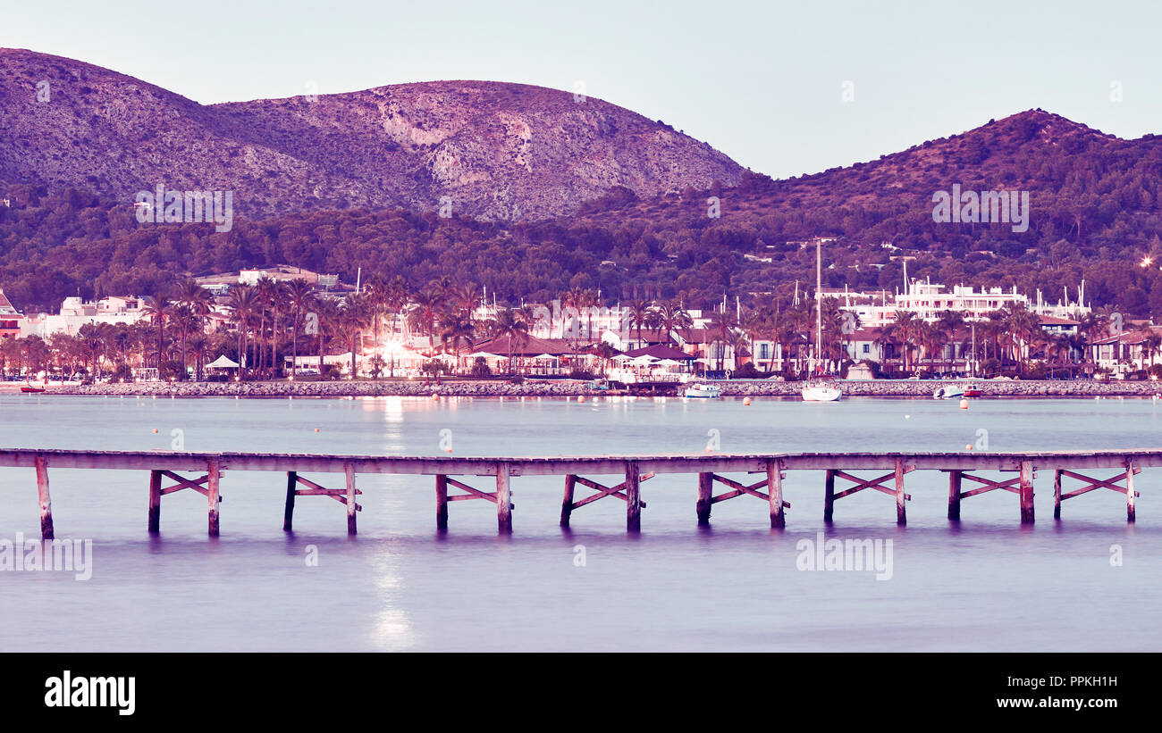 Farbe getonte Panoramabild eines hölzernen Pier, der Hafen von Alcudia im Hintergrund, Mallorca, Balearen, Spanien. Stockfoto