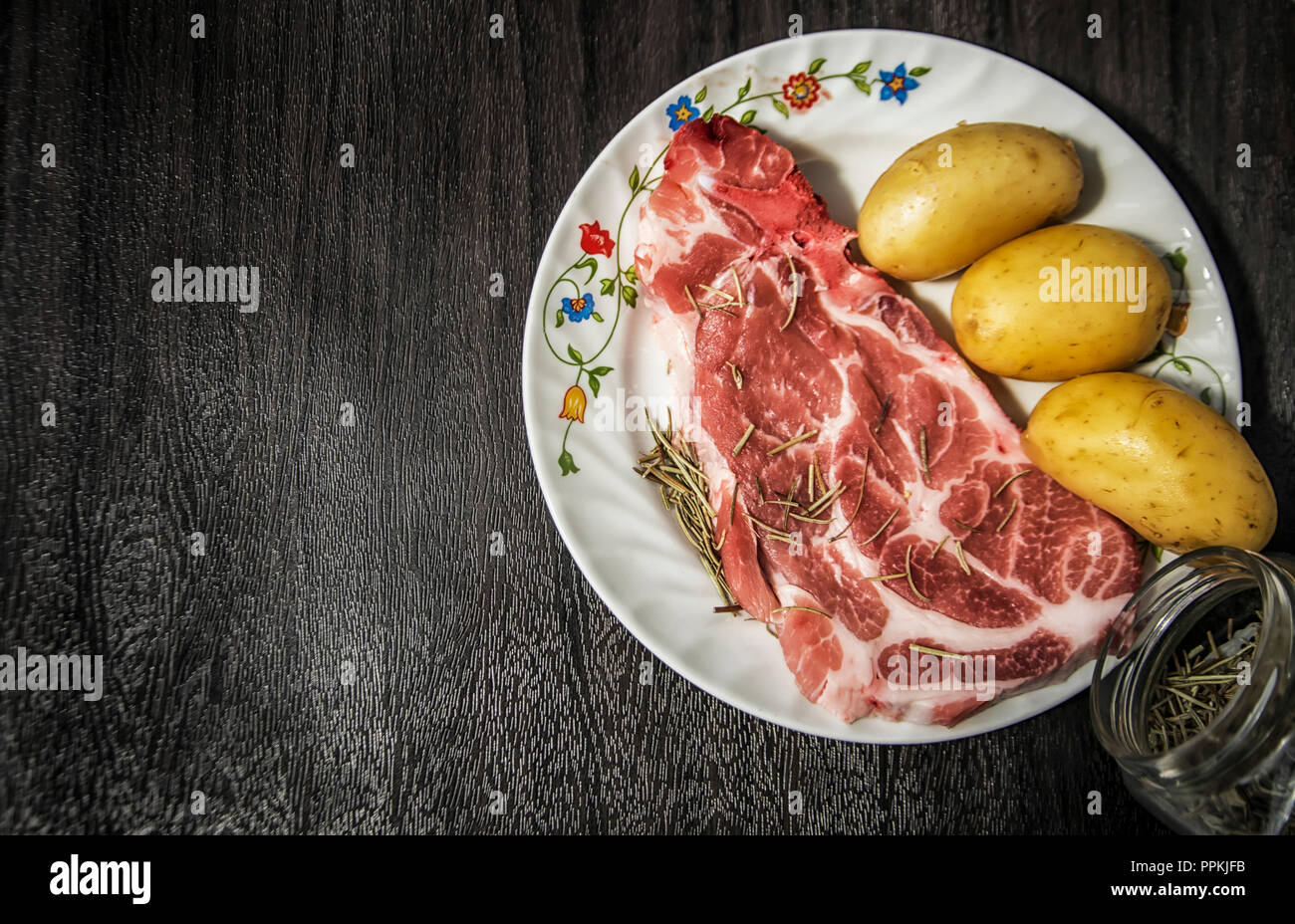 Rohes Schweinefleisch chop und Kartoffeln mit Rosmarin Stockfoto