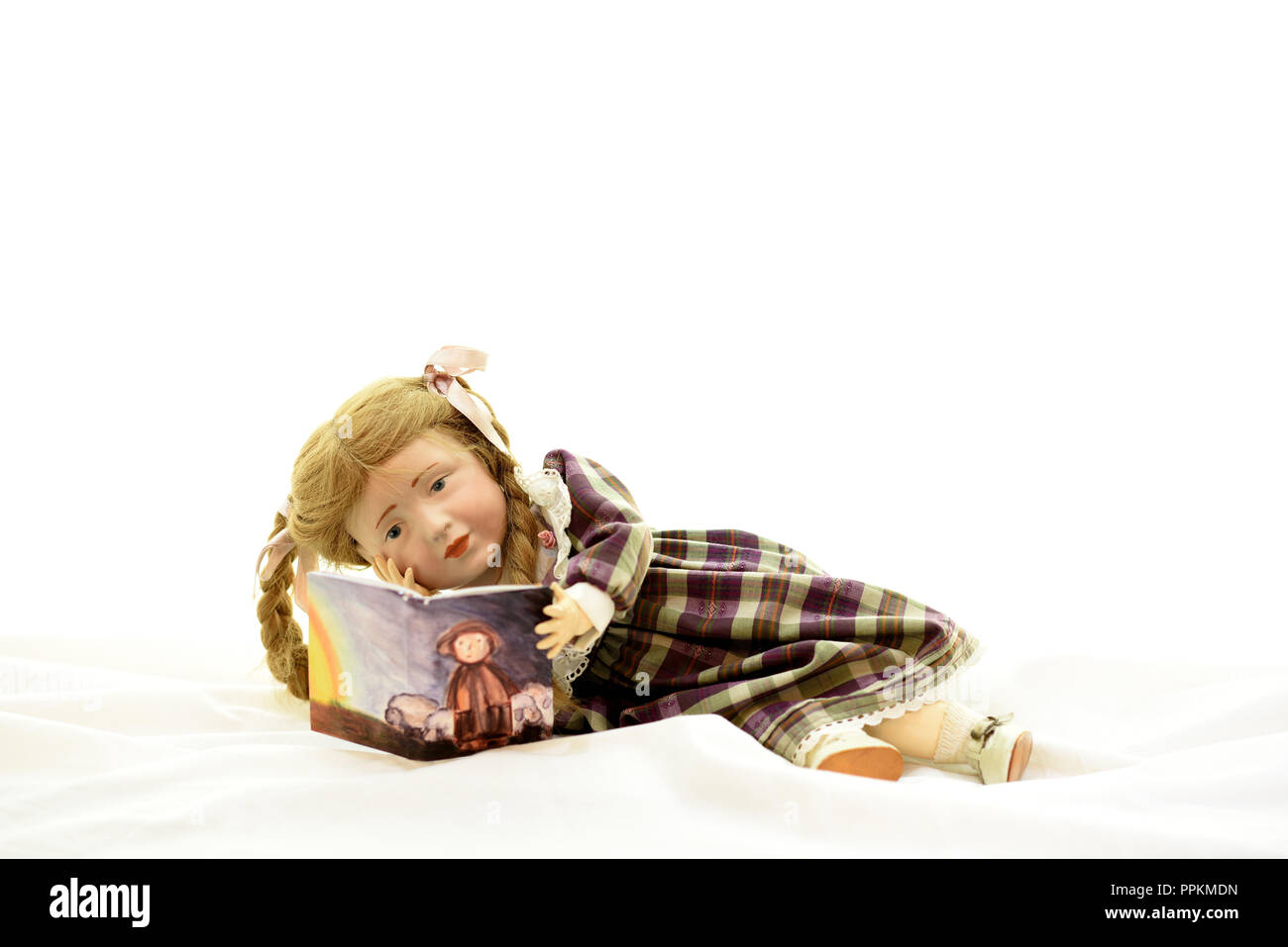 Puppe Elise liegt und liest ein Buch (Deutschland). Puppe Elise liegst liegend ein Buch (Deutschland). Stockfoto