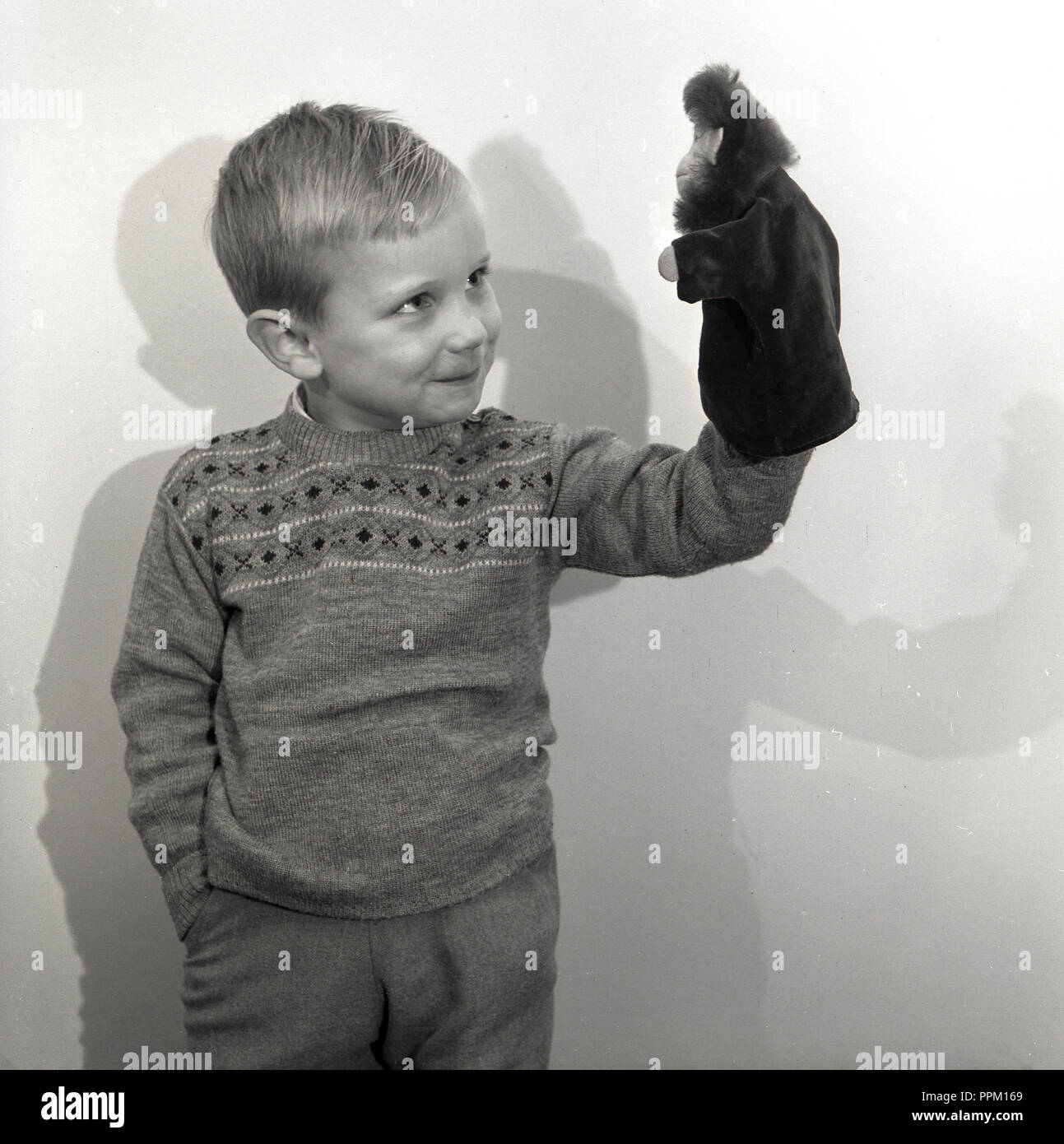 1960er Jahre, junge Junge spielt mit seinem plüschtier Affe Handschuh oder Handpuppe, England, UK. Puppenspiel im antiken Griechenland als eine Form von Theater entstanden. Stockfoto