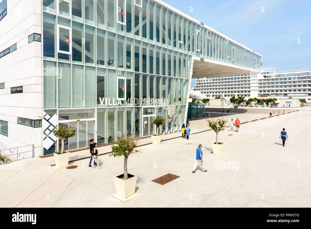 Die Villa Mediterranee, ein kulturelles Zentrum im Stadtteil La Joliette in Marseille, Frankreich, mit Menschen zu Fuß von einem Kreuzfahrtschiff in der Ferne und. Stockfoto