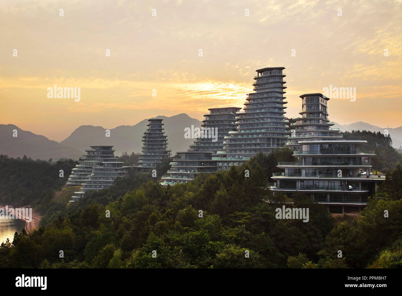 Silhouette Sonnenuntergang Ansicht des Gehäuses Cluster am Hang. Huangshan Dorf, Huangshan, China. Architekt: MAD Architekten, 2017. Stockfoto