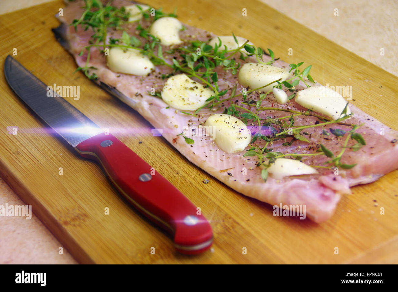 Frische rohe Forelle zum Backen. Fisch mit Kräutern, Knoblauch und Gewürze auf einem Holzbrett Stockfoto