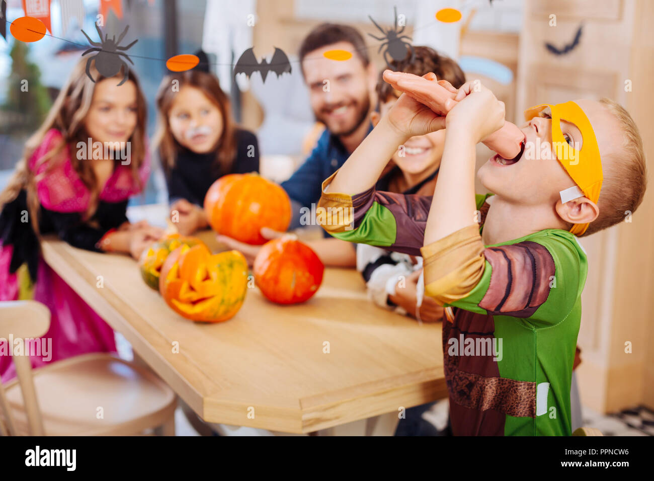 Schüler tragen gelbe Augenmaske für Halloween versucht, süsse Hand cookie Stockfoto