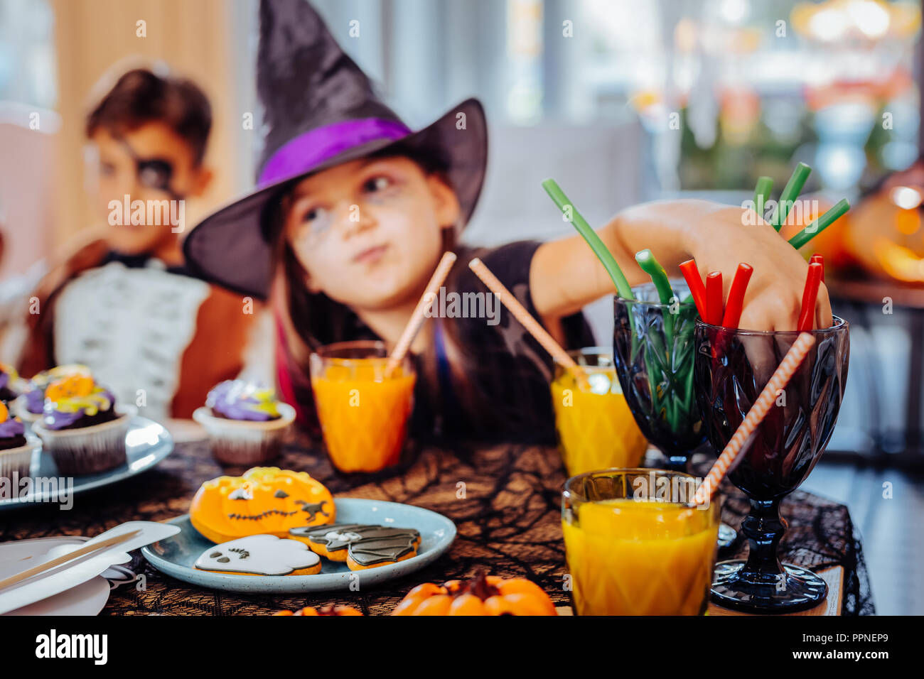 Mädchen mit Assistenten hat für Halloween Saft trinken und essen Gummibärchen Süßigkeiten Stockfoto