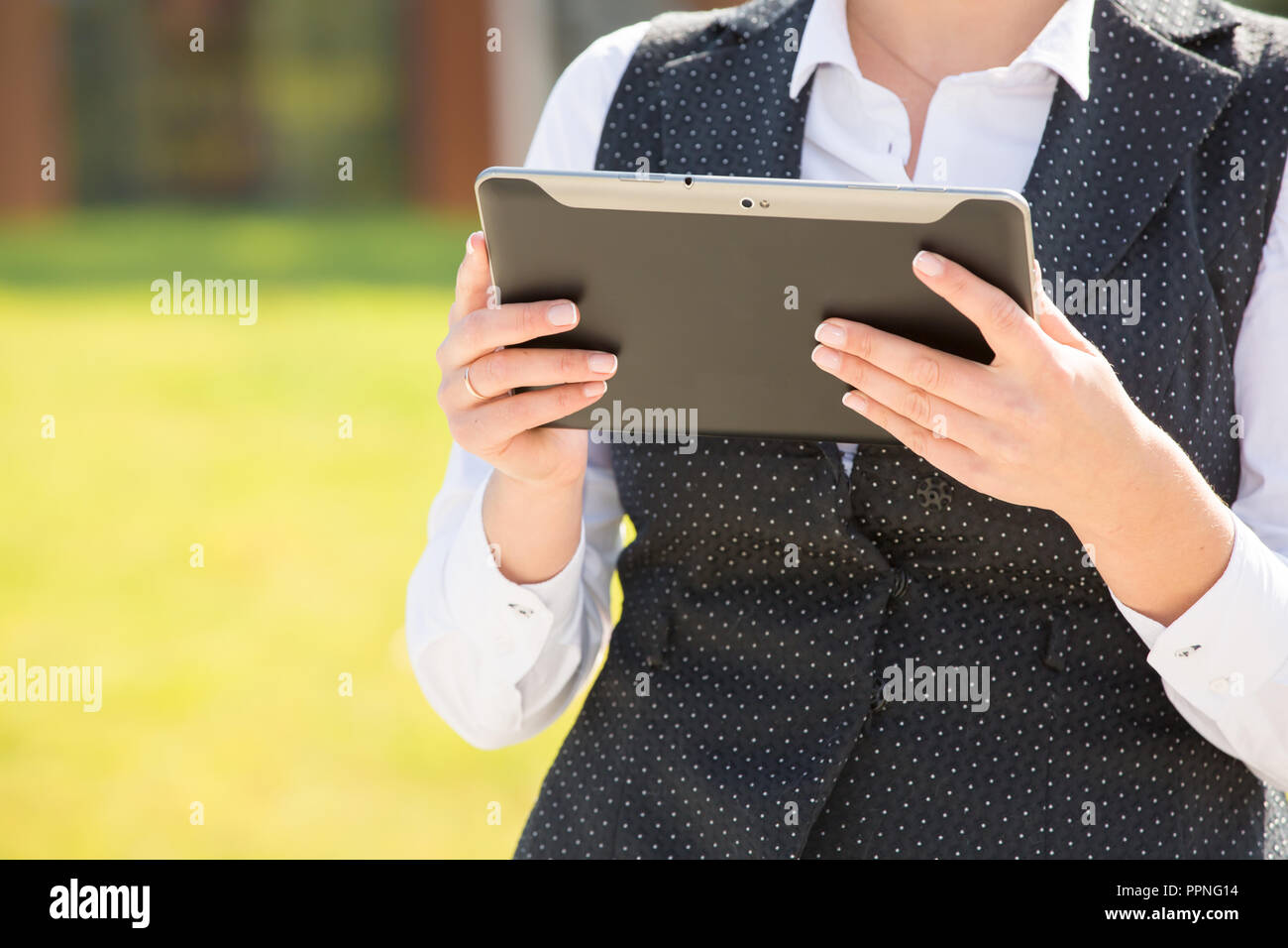 Business woman plus Größe steht auf dem Hintergrund eines Bürogebäudes mit einem Tablett in der Hand. Stockfoto