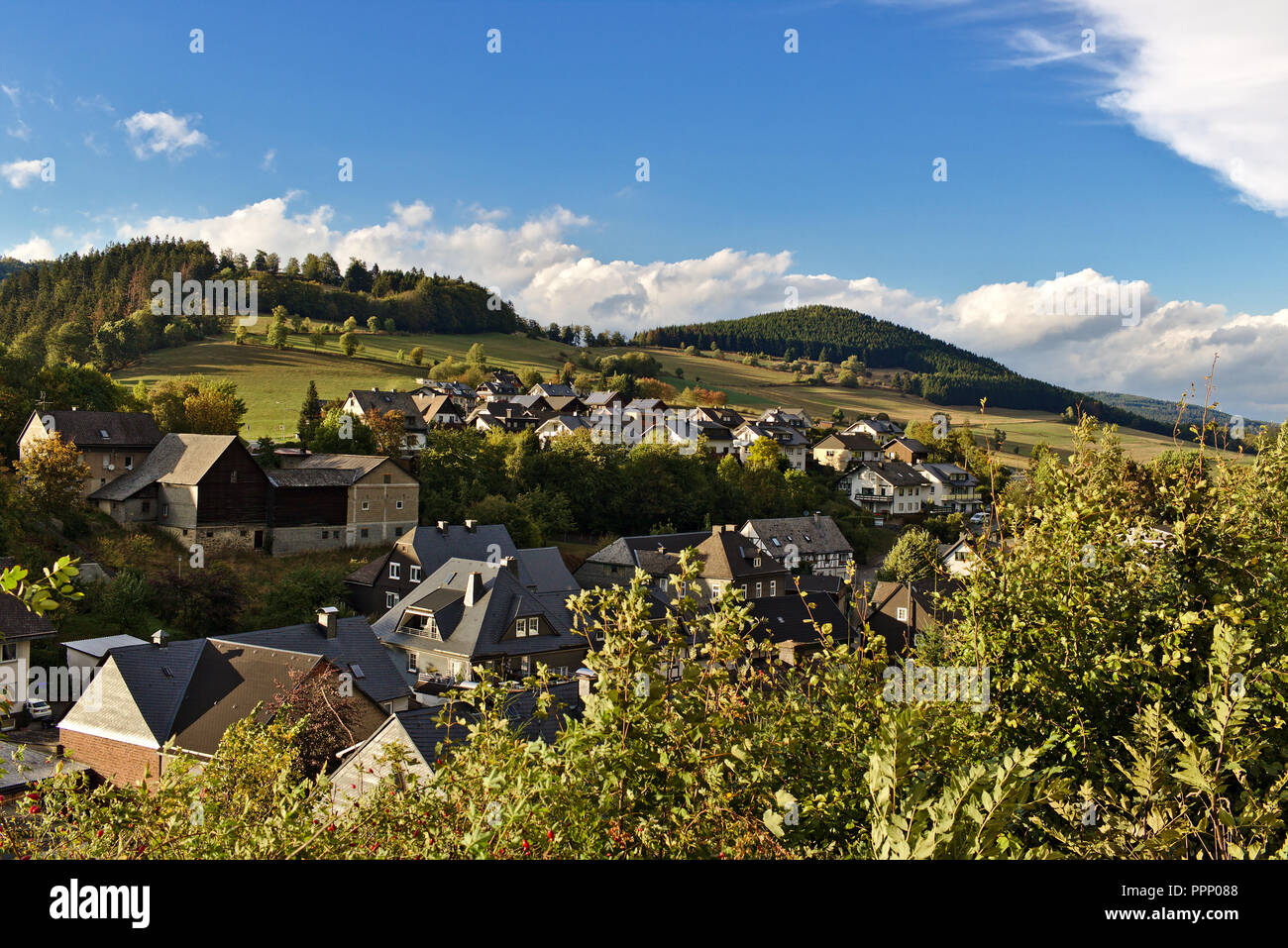 Schwalefeld, Deutschland - kleines Dorf in den grünen Hügeln der Region Sauerland mit bewaldeten Hügeln und blauen Himmel im Hintergrund eingebettet Stockfoto