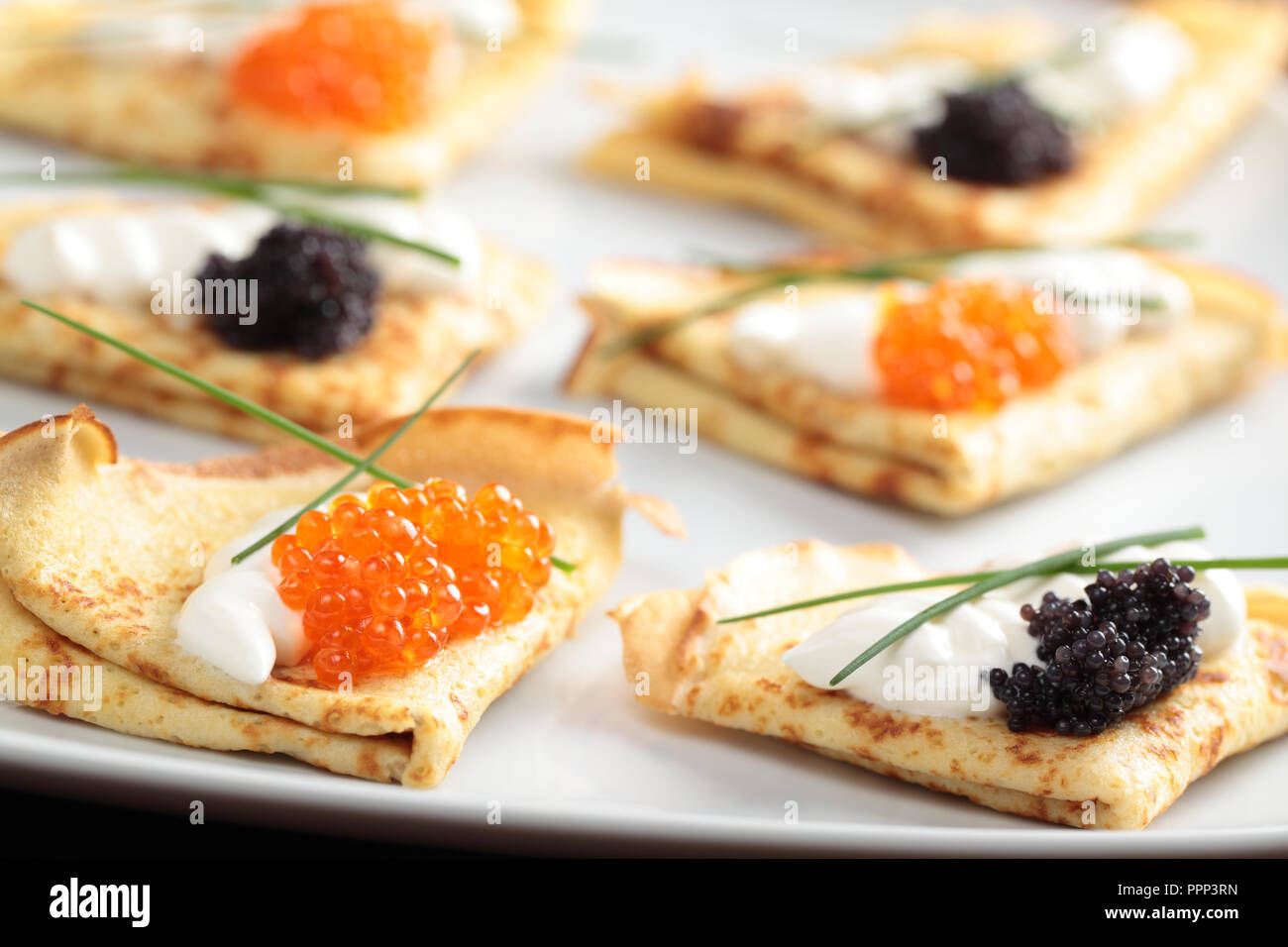 Crepes mit roter und schwarzer Kaviar auf einer Platte Stockfoto