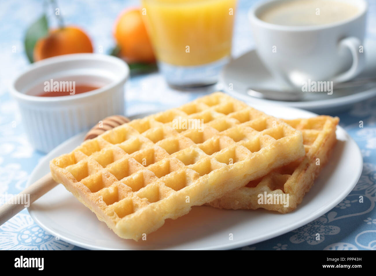 Frühstück mit belgischen Waffeln, Honig, Orangensaft und Kaffee Stockfoto