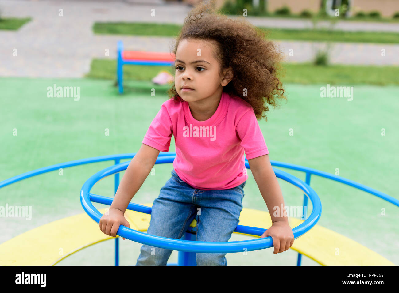 Curly afrikanische amerikanische Kind reiten auf Karussell am Spielplatz Stockfoto