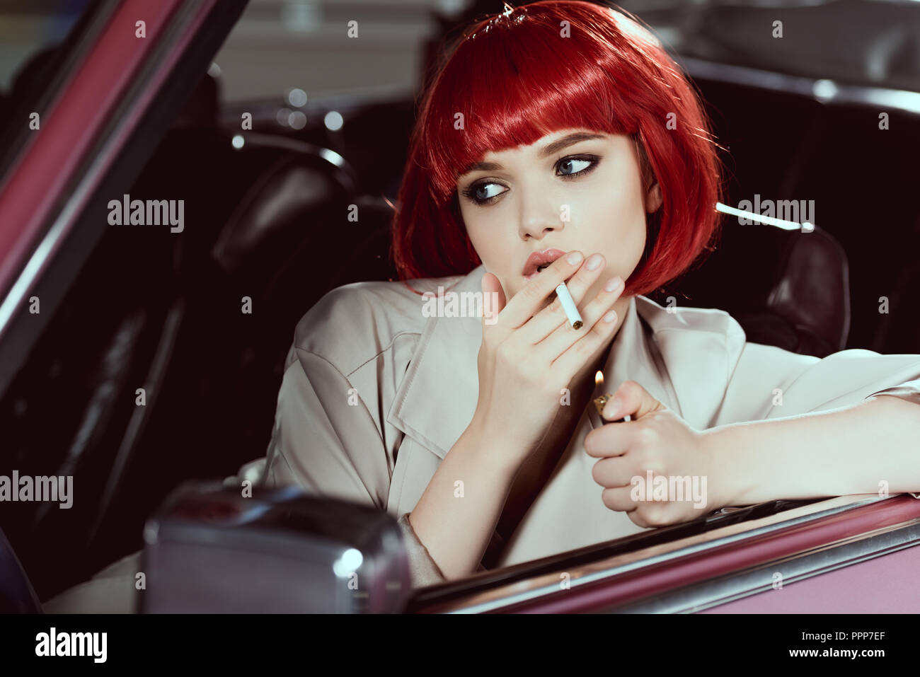 Attraktive Mädchen in Rot Perücke rauchen Zigarette und weg schauen, während im Auto sitzen Stockfoto