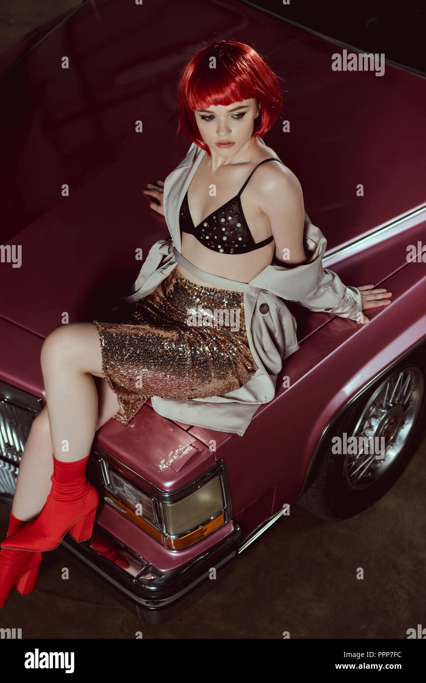Hohe Betrachtungswinkel und der schönen stilvollen Mädchen in Rot Perücke sitzen auf Classic Car Stockfoto