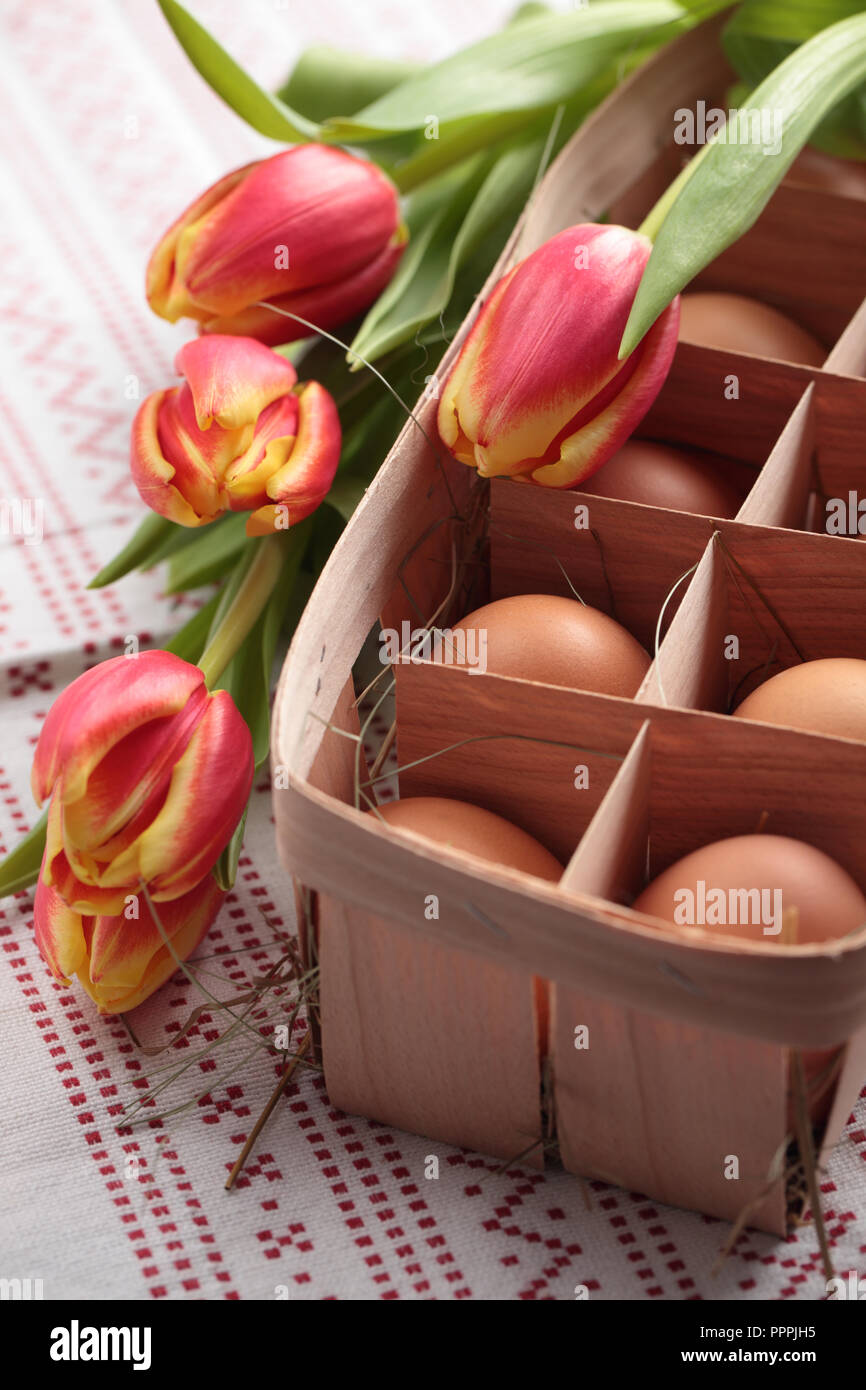 Eier in einen Korb und ein Bündel von Tulpen Stockfoto