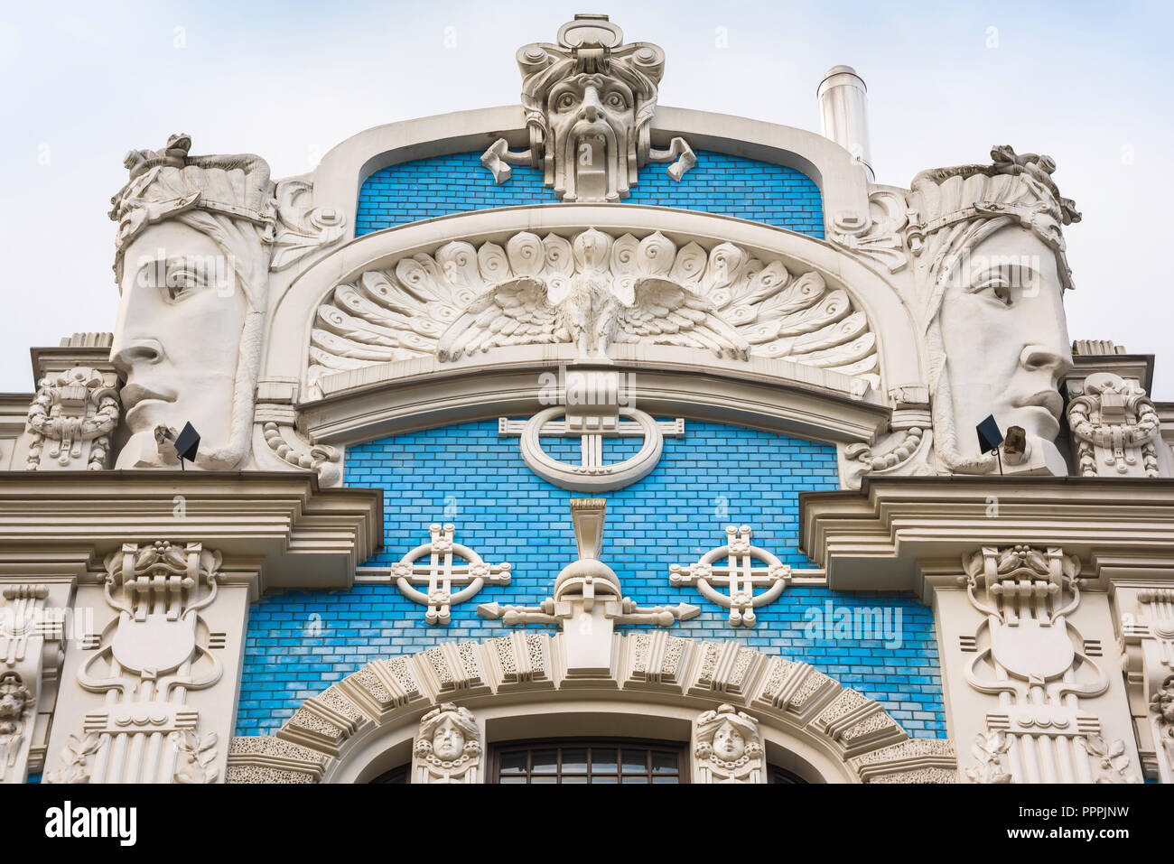 Riga Jugendstil Architektur, Detail von einem Giebel mit riesigen geschnitzten Köpfen und blauen Kacheln in Elizabetes Iela im Art Nouveau Stadtteil von Riga gelegen. Stockfoto