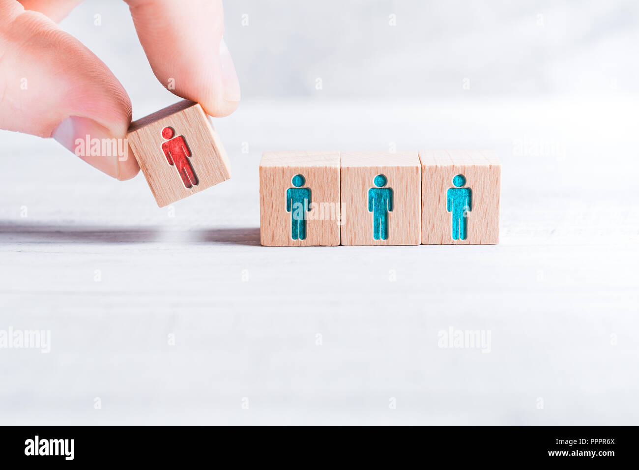 Männliche Finger Hinzufügen ein Block mit verschiedenen farbigen Mann Symbol 3 Blocks mit gleichen farbigen Mann Symbole auf einem Tisch-Leadership Konzept Stockfoto