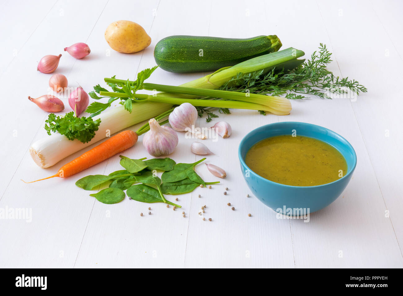 Türkis Schüssel Suppe mit Spinat und Zutaten, Gewürzen und Kräutern. Den Spinat treibt, Zwiebeln, Schalotten, Porree, Sellerie, Zucchini, Knoblauch, Petersilie, Ca Stockfoto