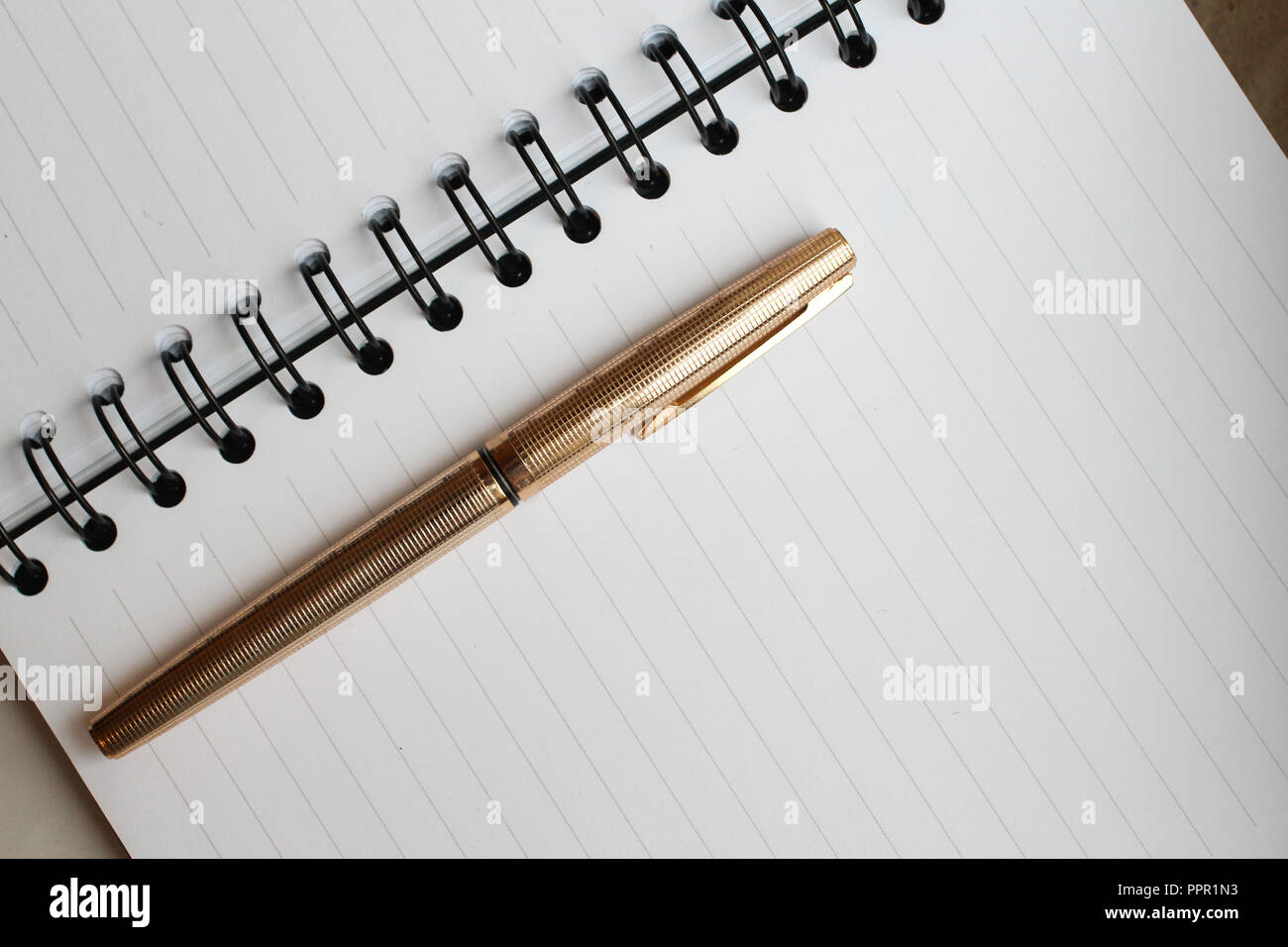Ein Notebook mit sauberer Bettwäsche, einen Umschlag und eine Goldene Feder auf dem Tisch Stockfoto