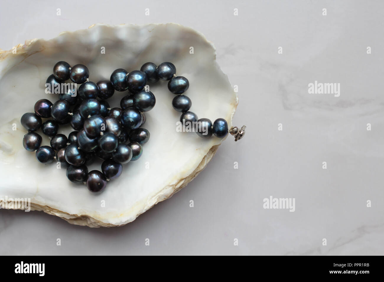 Makro Foto von Black Pearl Beads mit Steinen eine Shell, Marmor Hintergrund Stockfoto