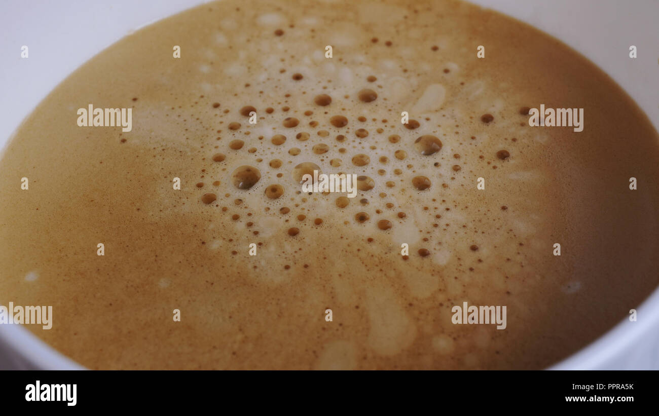 Extrem Nahaufnahme Blick auf die weißen Schale. Espresso mit Blasen Gießen von professionellen Kaffeemaschine. Kaffeemaschine. Moderne Technologie Konzept Stockfoto