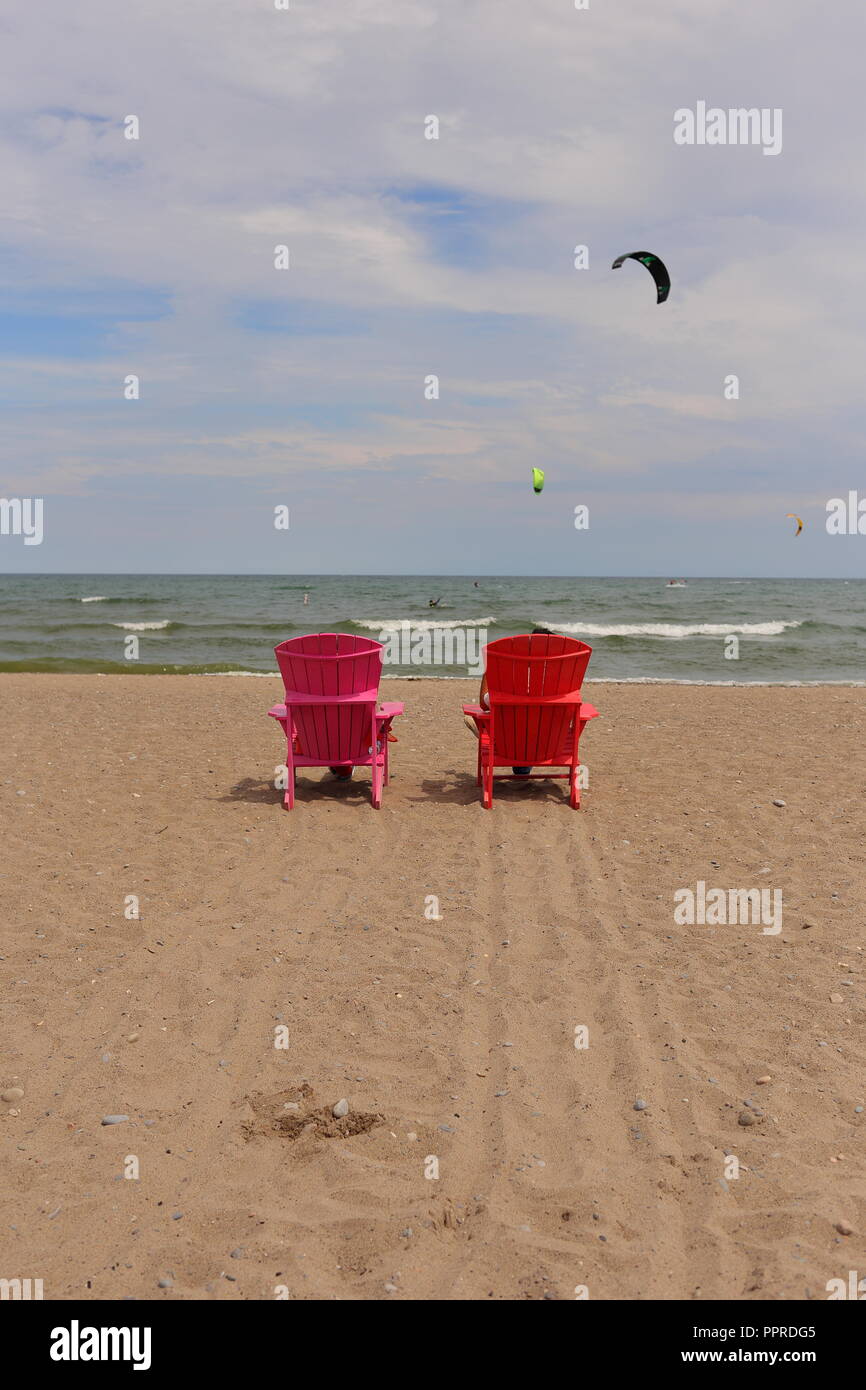 Schuss nicht Klappbare Stühle von hinten gesehen an einem einsamen Strand. Es gibt zwei Fallschirme in den Himmel. - Woodbine Strand, Toronto, CA Stockfoto